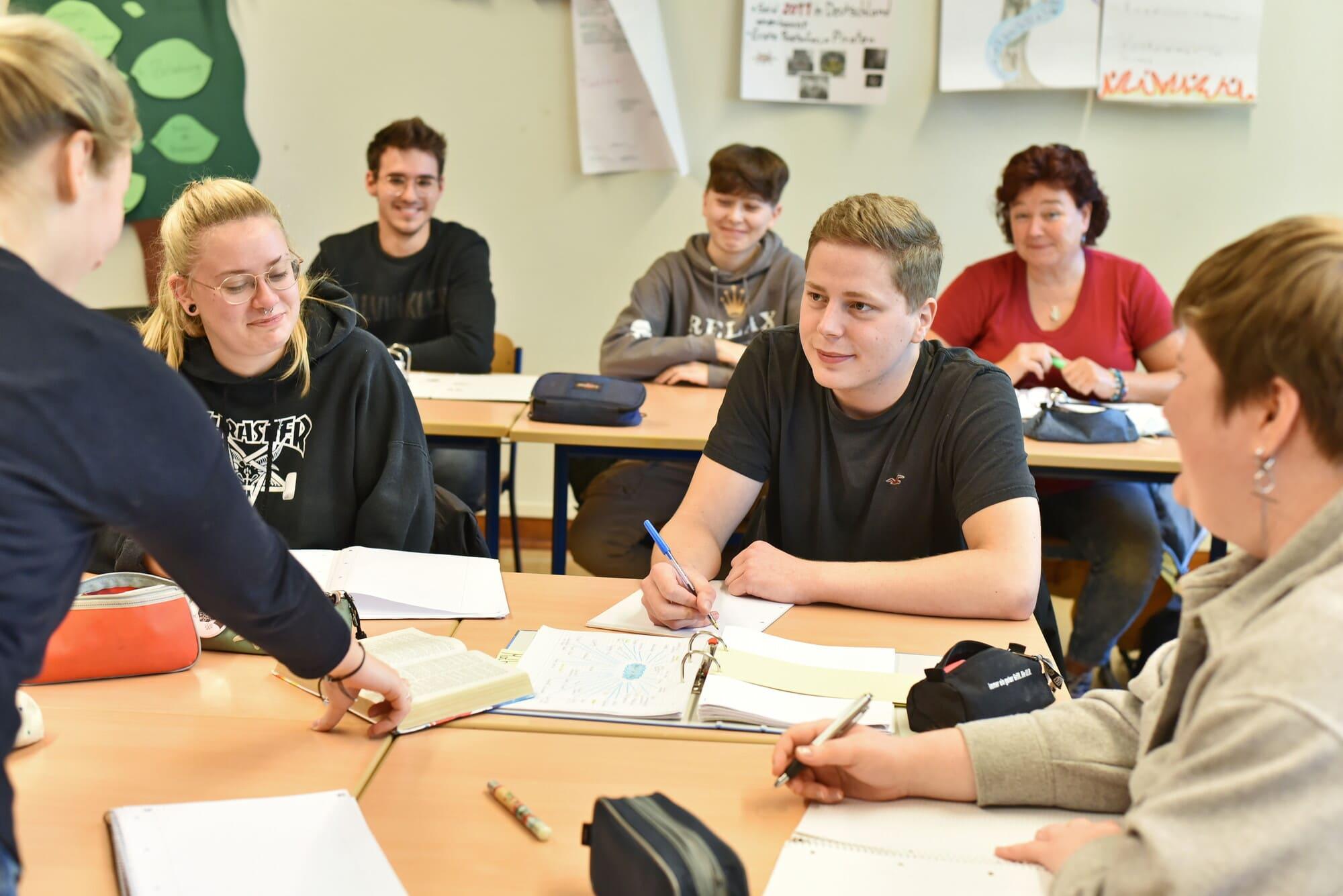 Religionsunterricht in einer Schule Schüllerinnen und Schüler sitzen während des Religionsuntertischt im Klassenraum bei einer Gruppenarbeit an zusammengestellten Tischen.