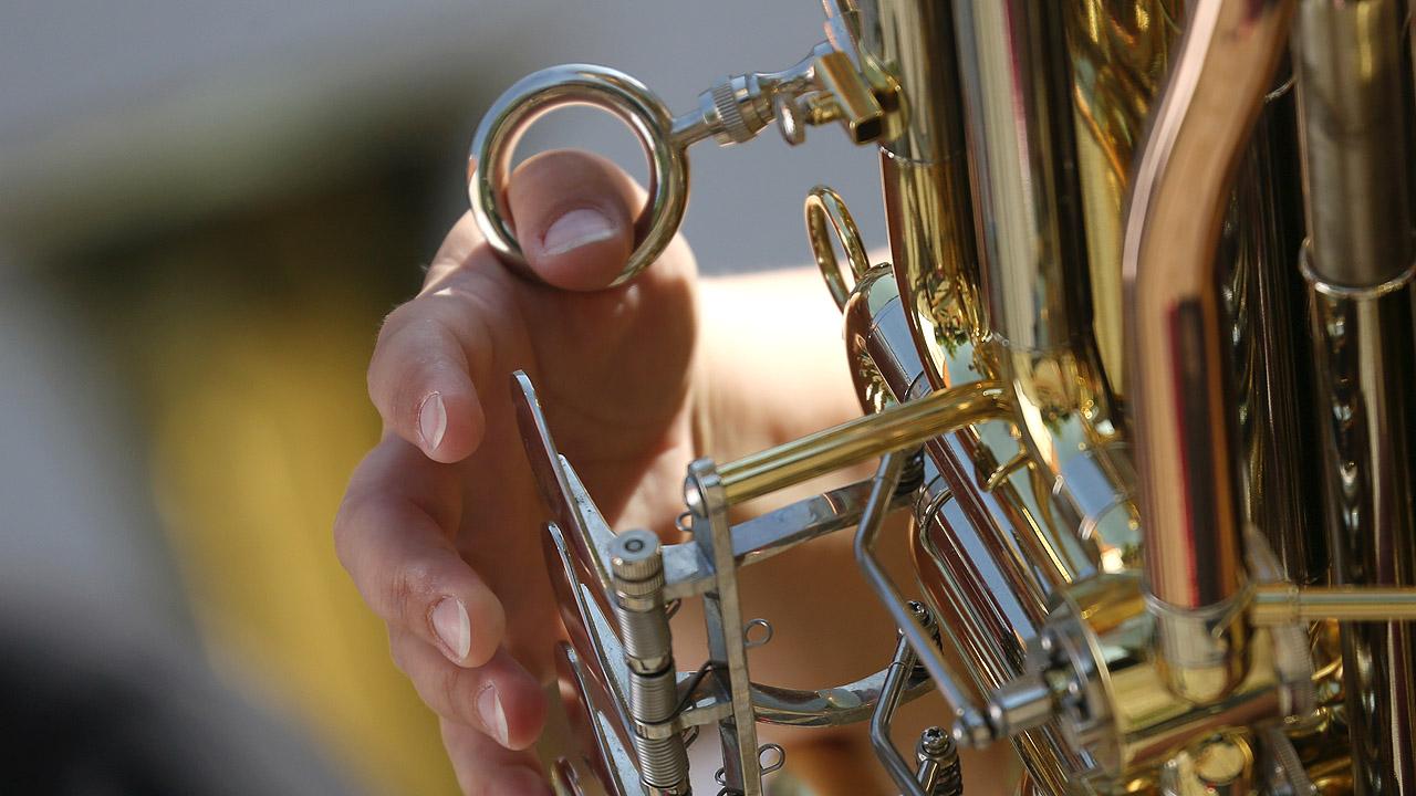 Hände an den Tasten eines Blechblasinstrumentes