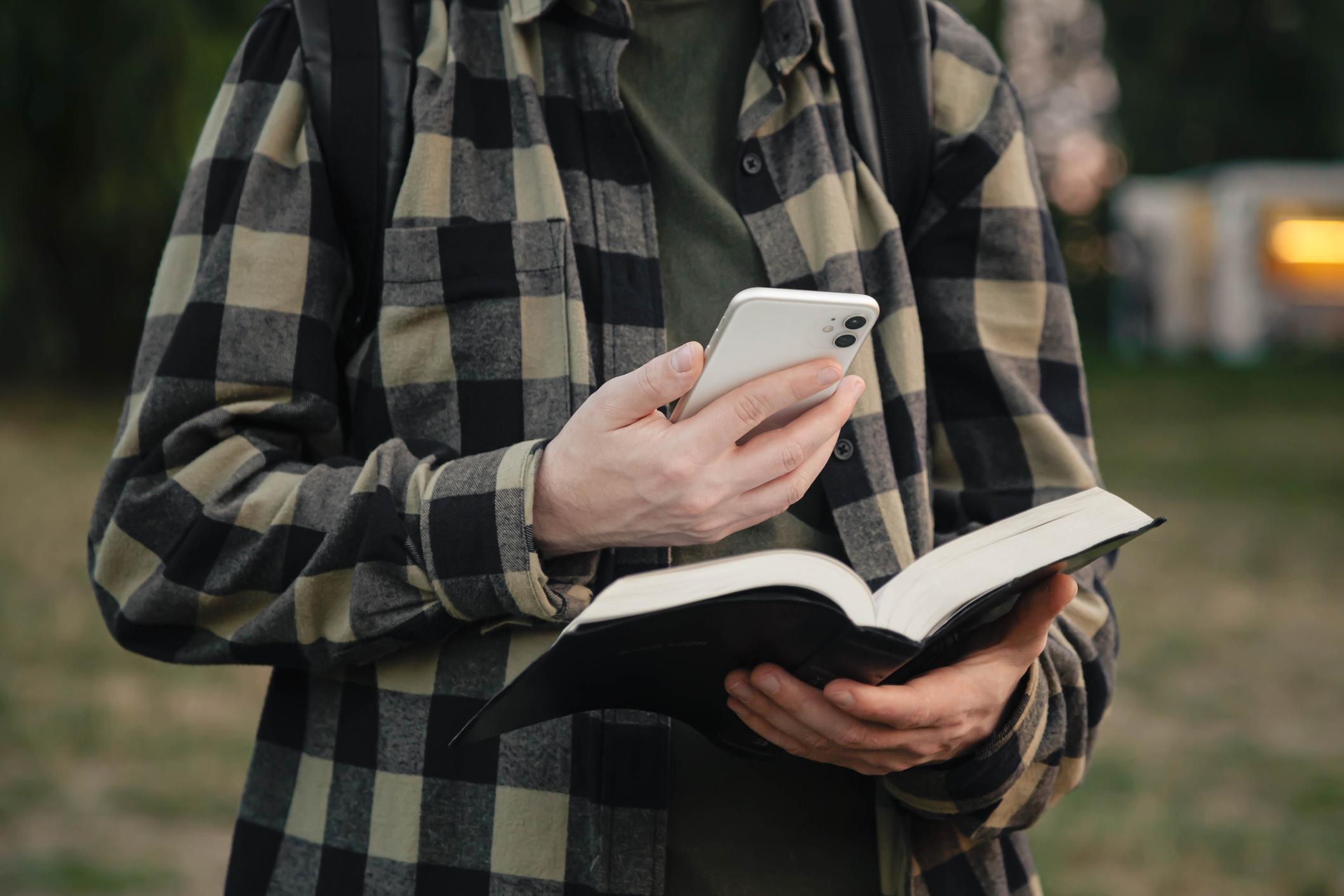 Mann mit Handy und Bibel.