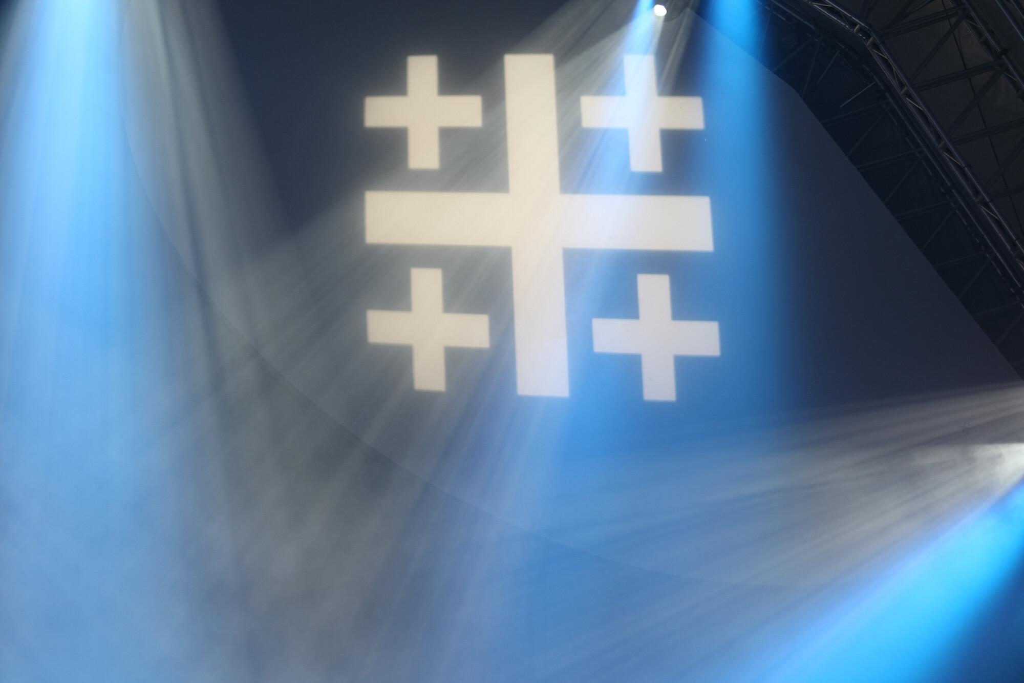 Kirchentag - Jerusalemkreuz Ein Jerusalemkreuz wird in einer blauen Halle projiziert und Scheinwerfer bestrahlen es