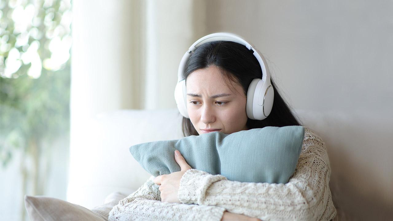 Ein trauriges Mädchen hört über Kopfhörer Musik
