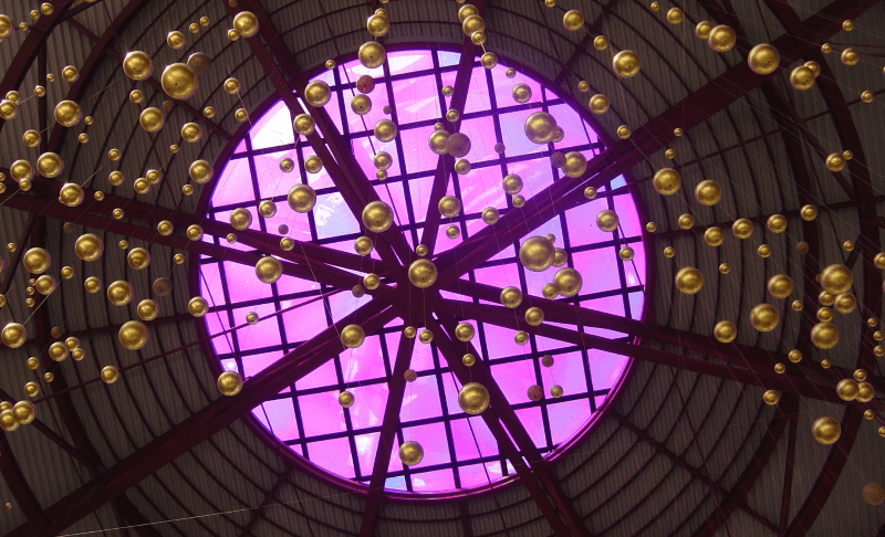 viele goldene Kugeln hängen unter dem Dachfenster, das magenta erscheint