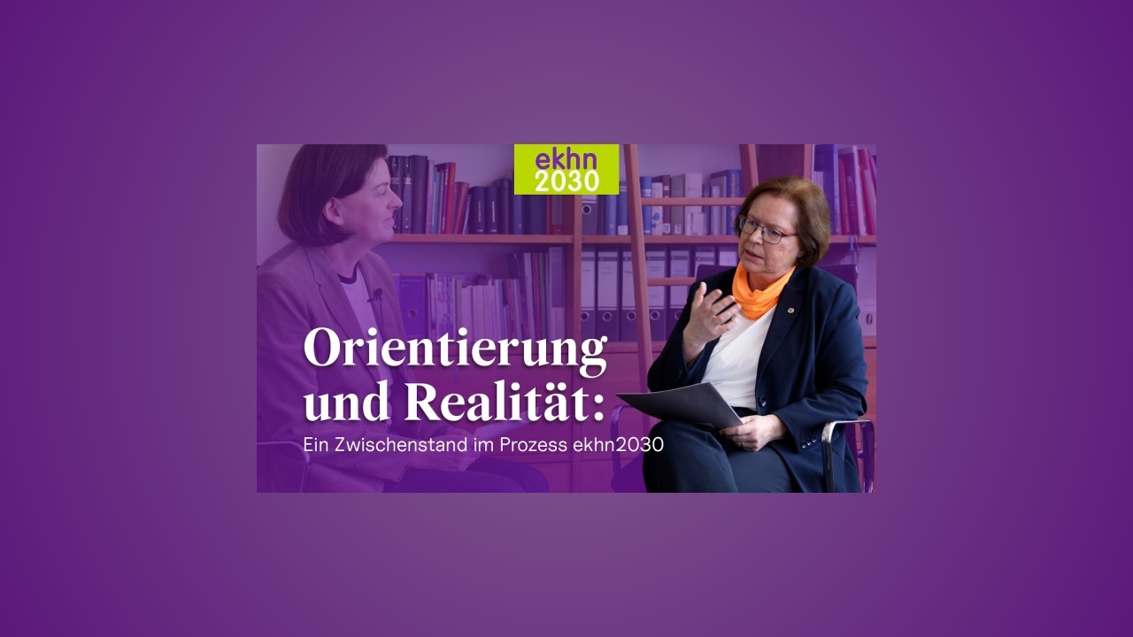 Orientierung und Realität: Ein Zwischenstand im Prozess ekhn2030 Zwei Frauen im Gespräch in einem Büro mit Bücherregalen; Einblendung: ‚Orientierung und Realität – Zwischenstand im Prozess ekhn2030‘.