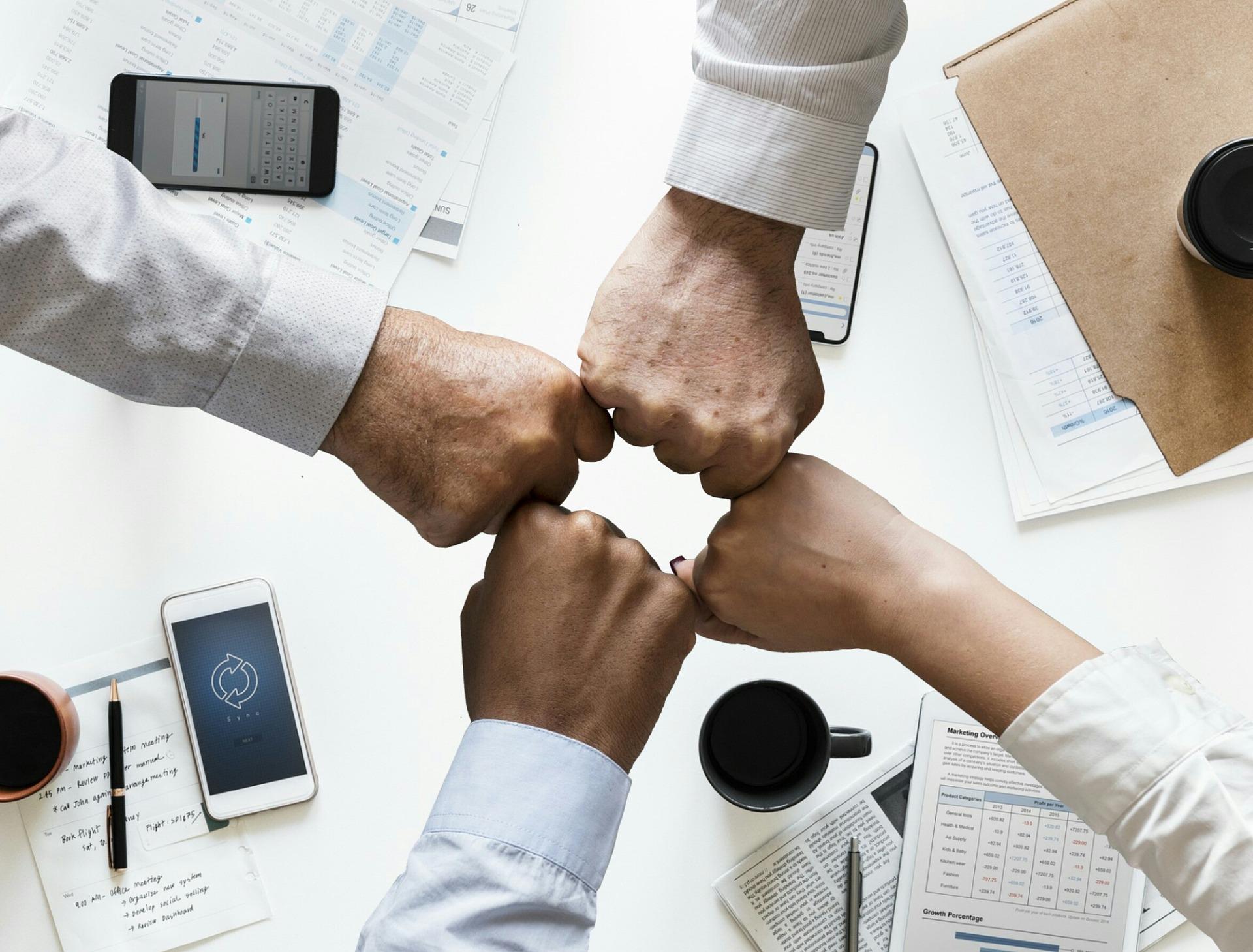 Teamwork Vier aneinandergehaltene Fäuste als Zeichen der Zusammengehörigkeit
