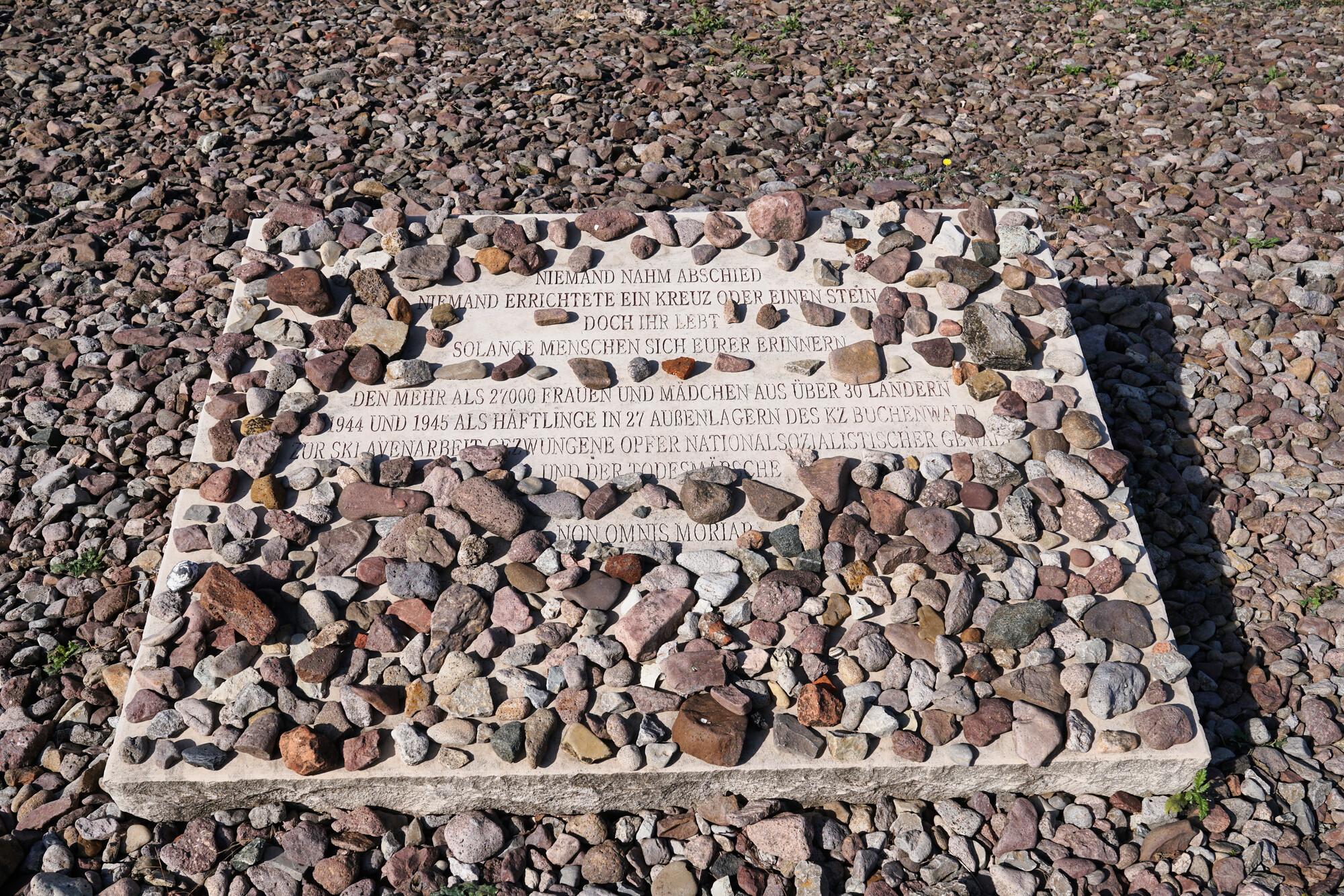 KZ Gedenkstätte Buchenwald KZ Gedenkstätte Buchenwald. Eine Gedenkplatte mit Text liegt auf Kieselsteinen.