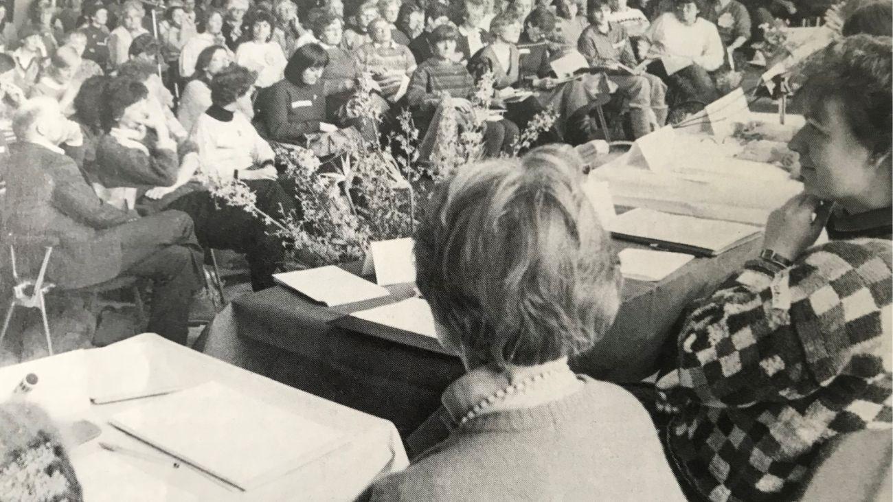 Erste Frauenanhörungin der EKHN Im Saal sitzen viele Frauen die auf ein Podium blicken, auf dem Podium sieht man zwei Frauen von hinten. Das Bild ist schwarz-weiß.