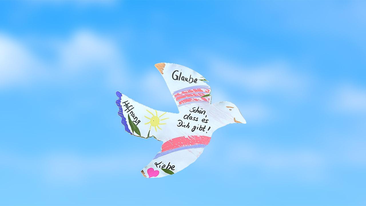 Papiervogel mit Worten wie Glaube, Liebe, Hoffnung vor blauem Himmel