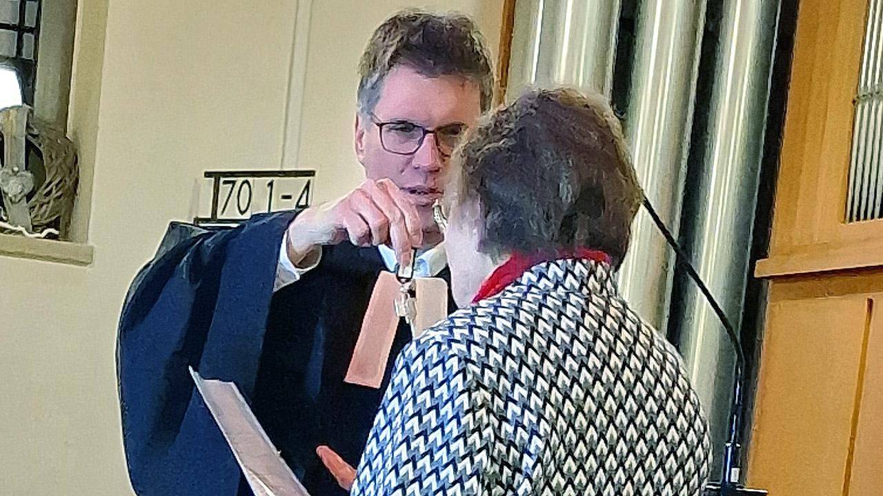 Schlüsselübergabe Ein evangelischer Pfarrer übergibt einen Schlüsselbund an eine ältere Dame