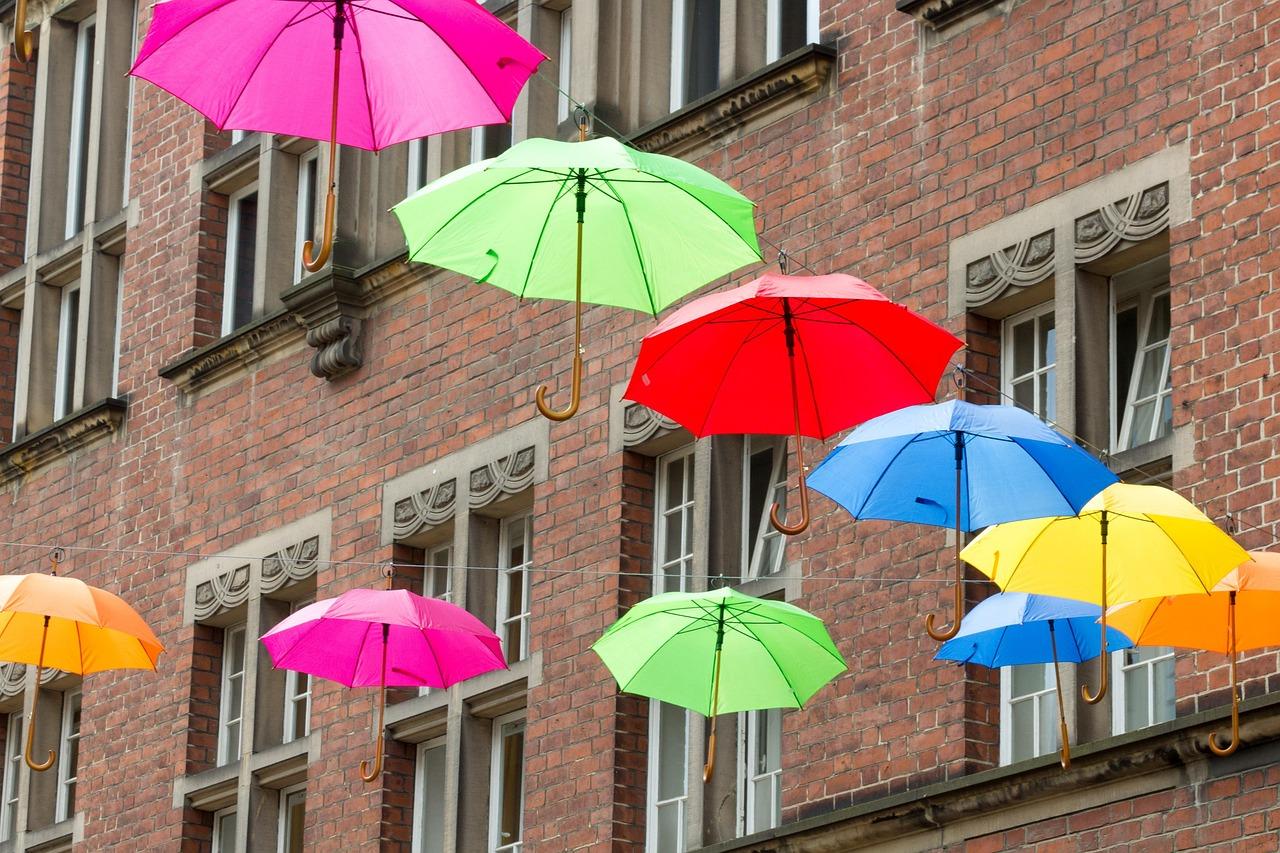 Bunte Schirme Bunte Regenschirme, die an einer Leie aufgehängt sind