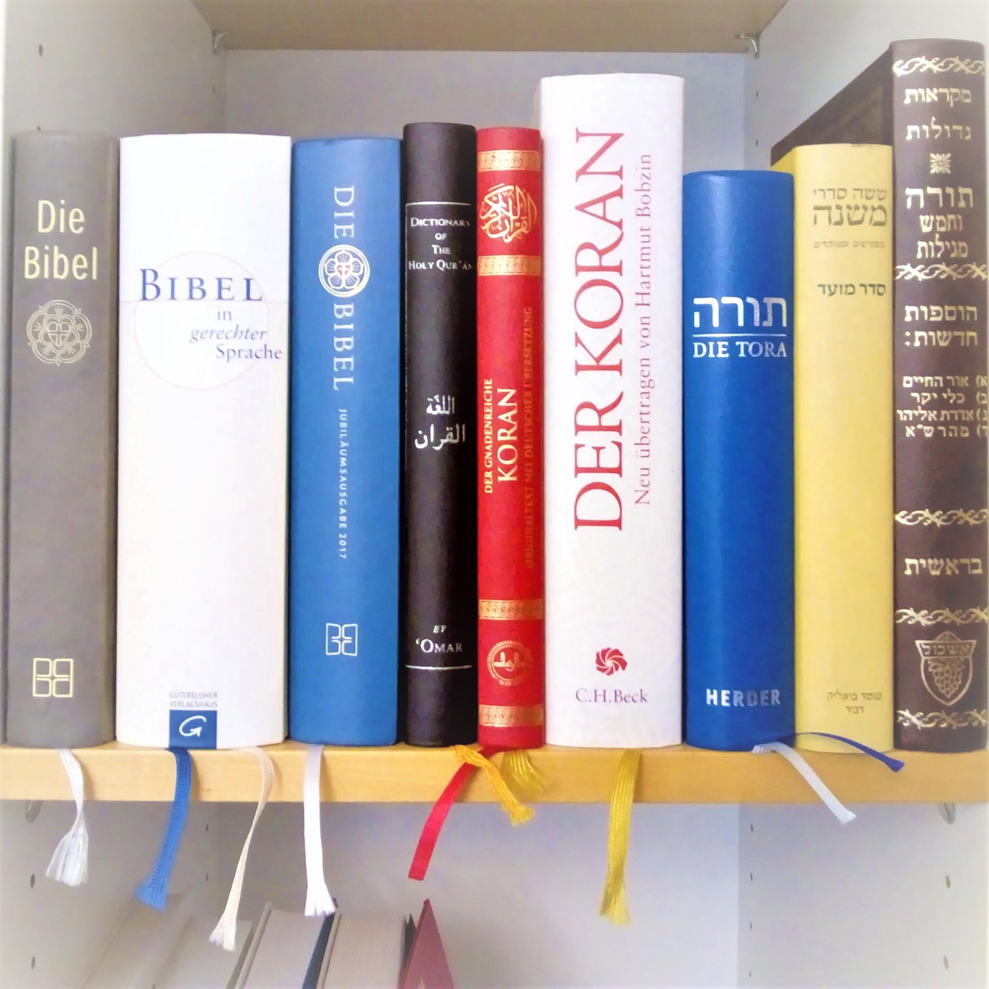 Heilige Schriften In einen Bücherregal stehen nebeneinander je drei verschiedene Ausgaben der Bibel, des Korans sowie zwei Ausgaben der Tora und eine Mischna