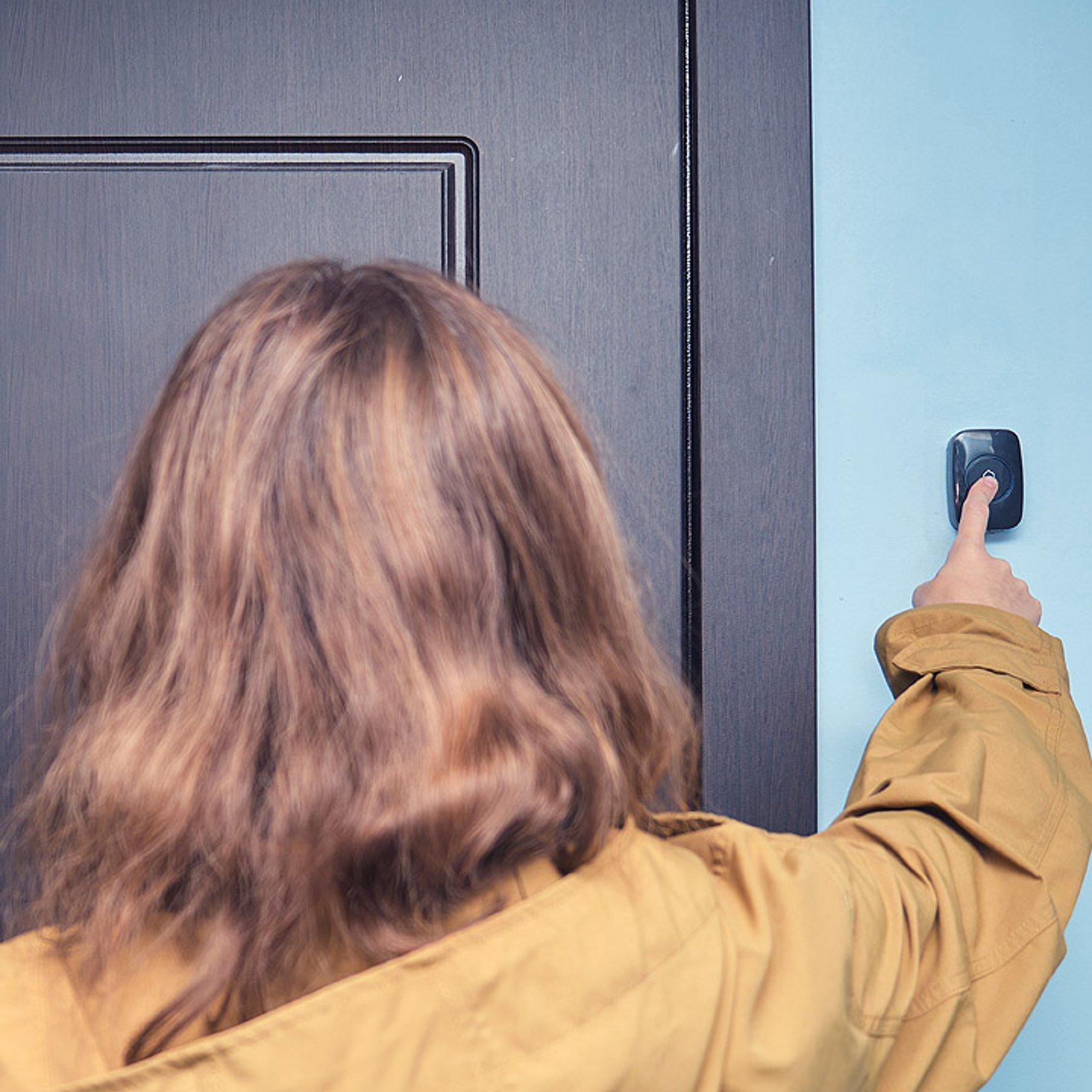 An einer Tür klingeln Eine Frau klingelt an einer Tür