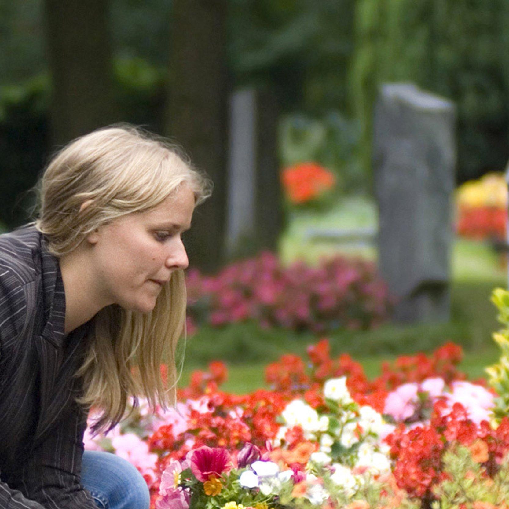 Grab mit Blumen Eine junge Frau an einem Grab mit Blumen