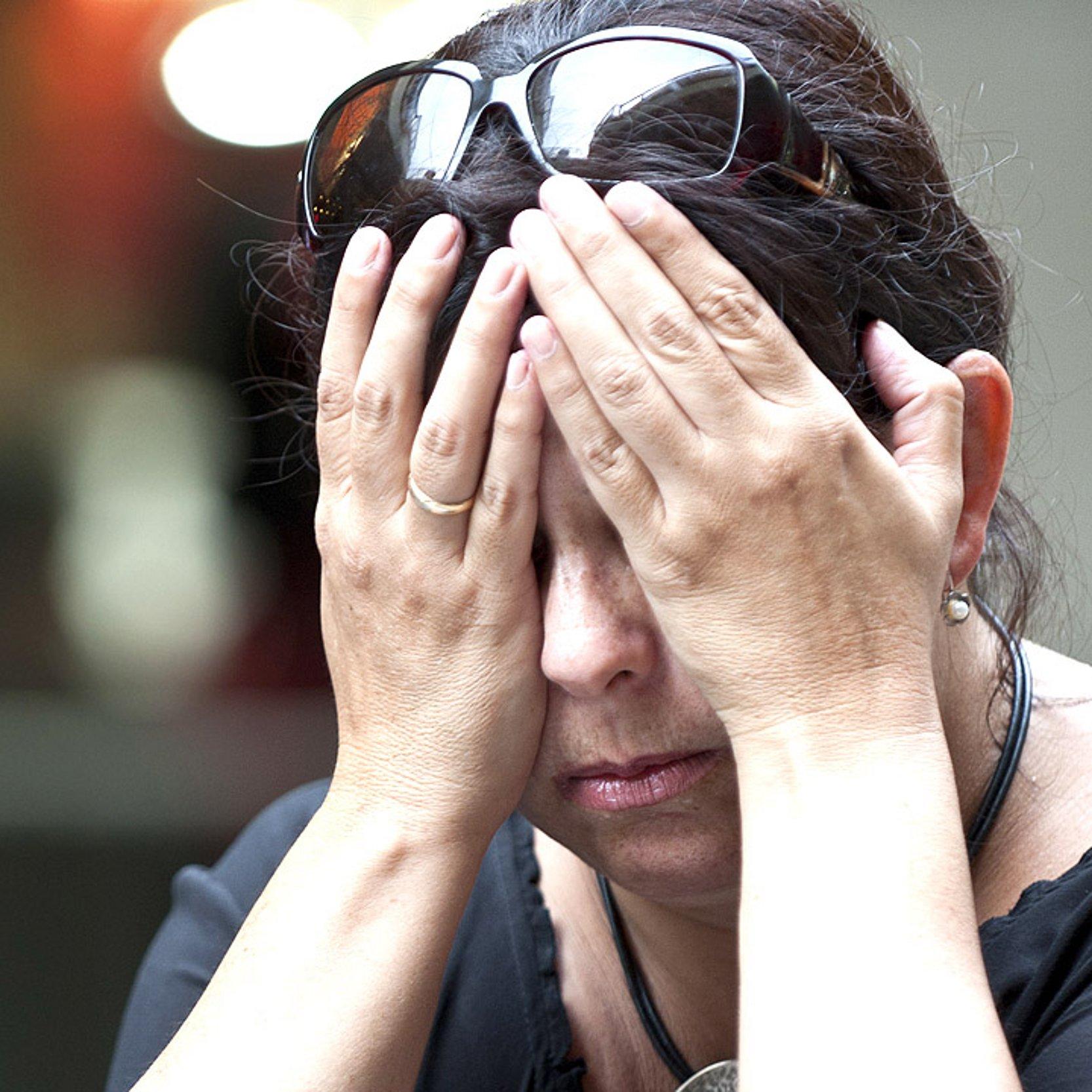 Verzweiflung Eine Frau mittleren Alters hält die Hände vor das Gesicht