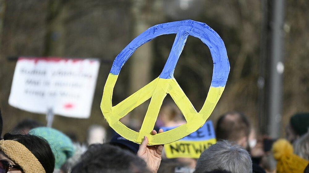 Ein buntes Friedenszeichen wird bei einer Demonstration für Frieden in der Ukraine hochgehalten.