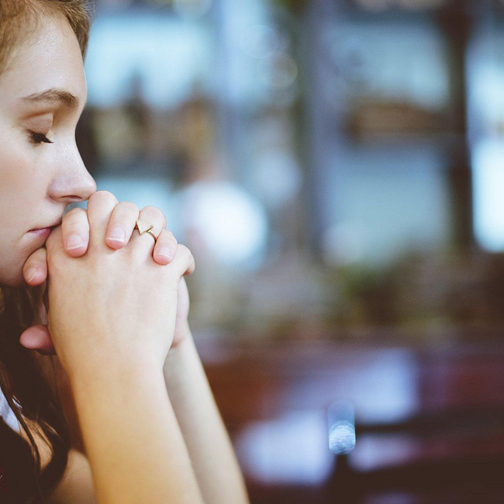 junge Frau betet mit geschlossenen Augen