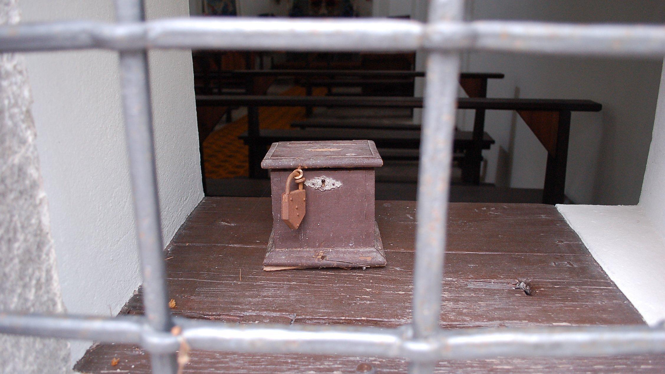 Hinter einem Gitter steht eine alte Geldtruhe oder Spartruhe