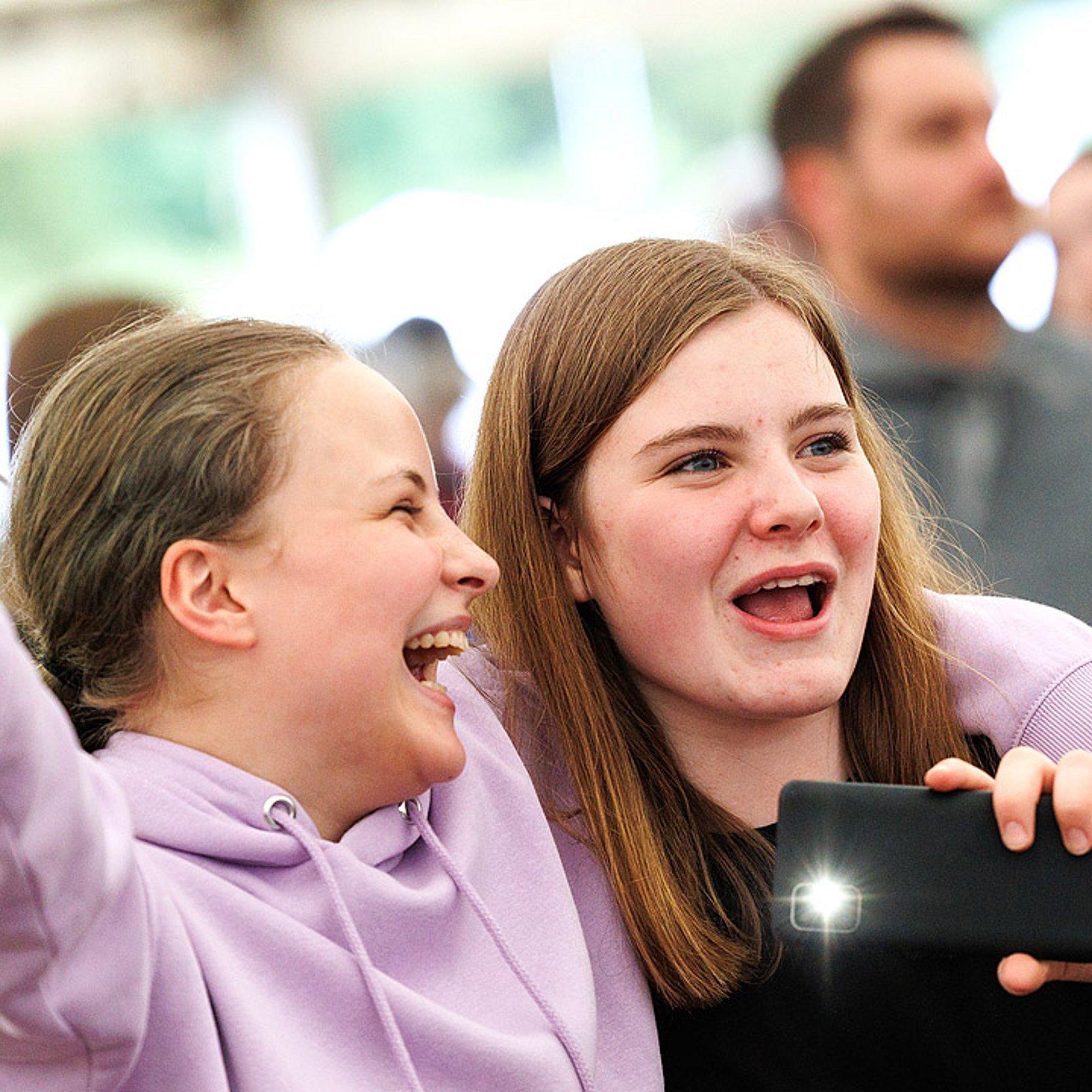 Jugendkirchentag - gute Stimmung Ein Mädchen legt den Arm um ein anderes, beide freuen sich