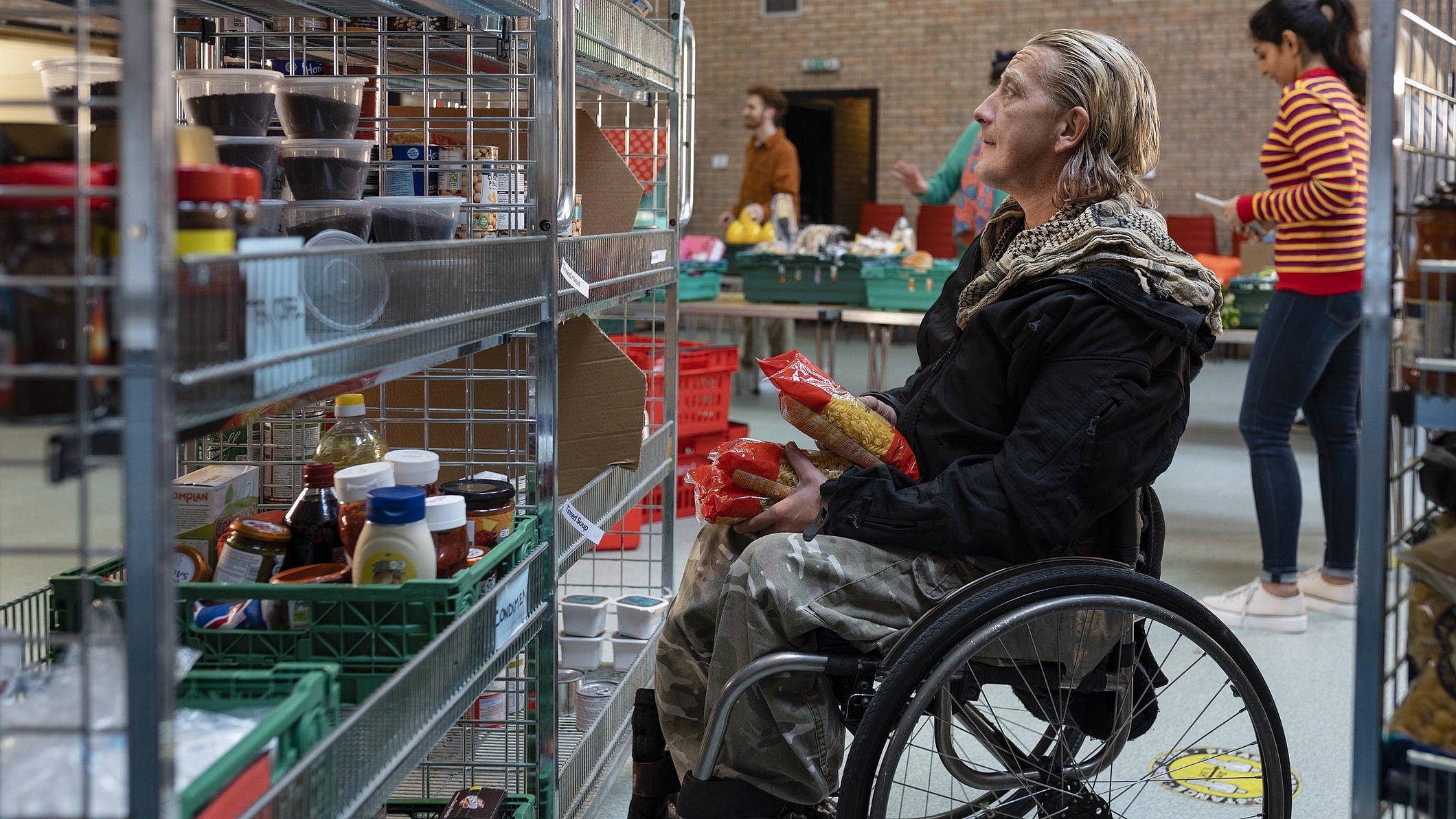 Ein Rollstuhlfahrer vor einem Regal mit Lebensmitteln