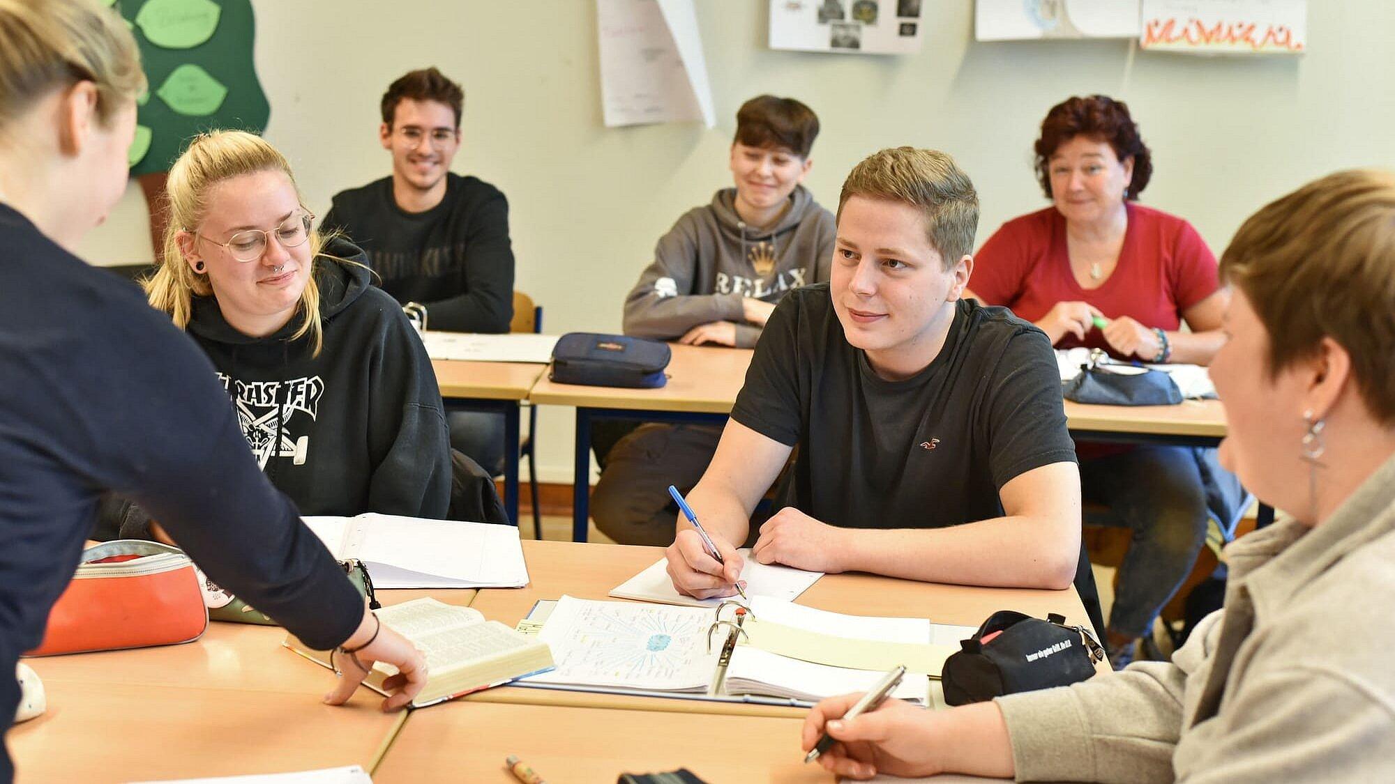 Schüllerinnen und Schüler sitzen während des Religionsuntertischt im Klassenraum bei einer Gruppenarbeit an zusammengestellten Tischen.