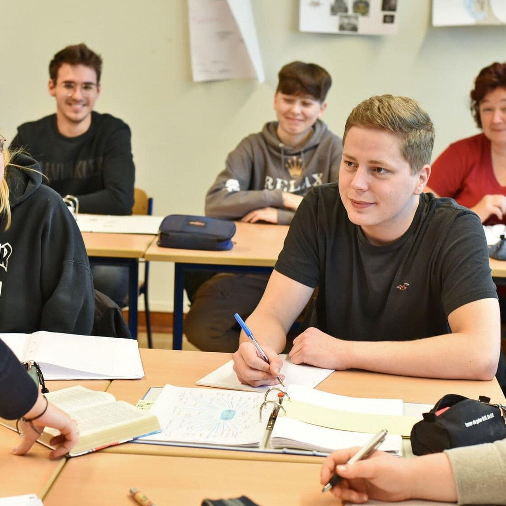 Religionsunterricht in einer Schule Schüllerinnen und Schüler sitzen während des Religionsuntertischt im Klassenraum bei einer Gruppenarbeit an zusammengestellten Tischen.
