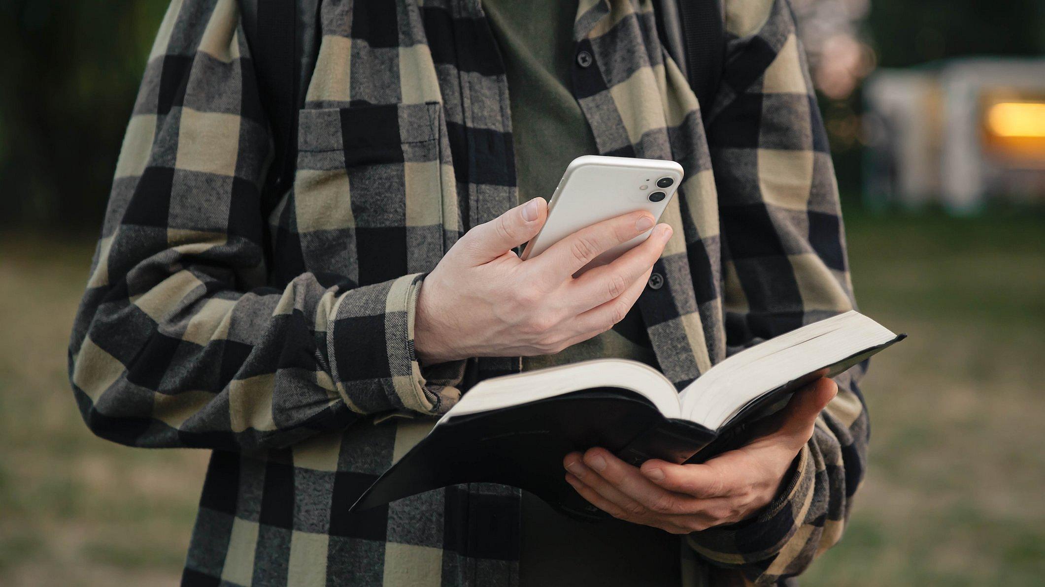 Mann mit Handy und Bibel.