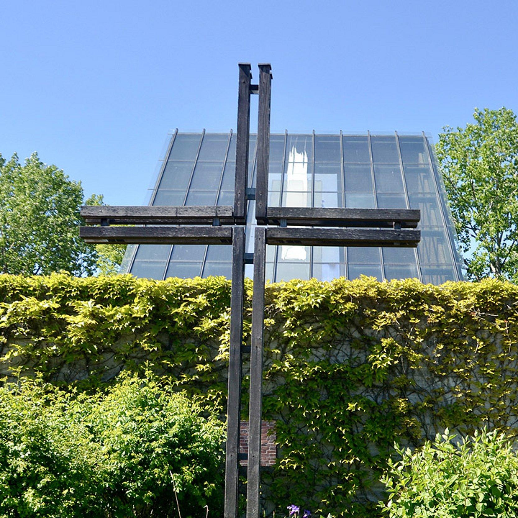 Autobahnkirche Medenbach Autobahnkirche Medenbach: Mit Efeu bewachsene Mauer, dahinter ein Kreuz und ein schräges Glasdach