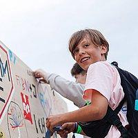 Jugendkirchentag Ein Junge ist an einem Turm hochgekletter und gestaltet dort etwas