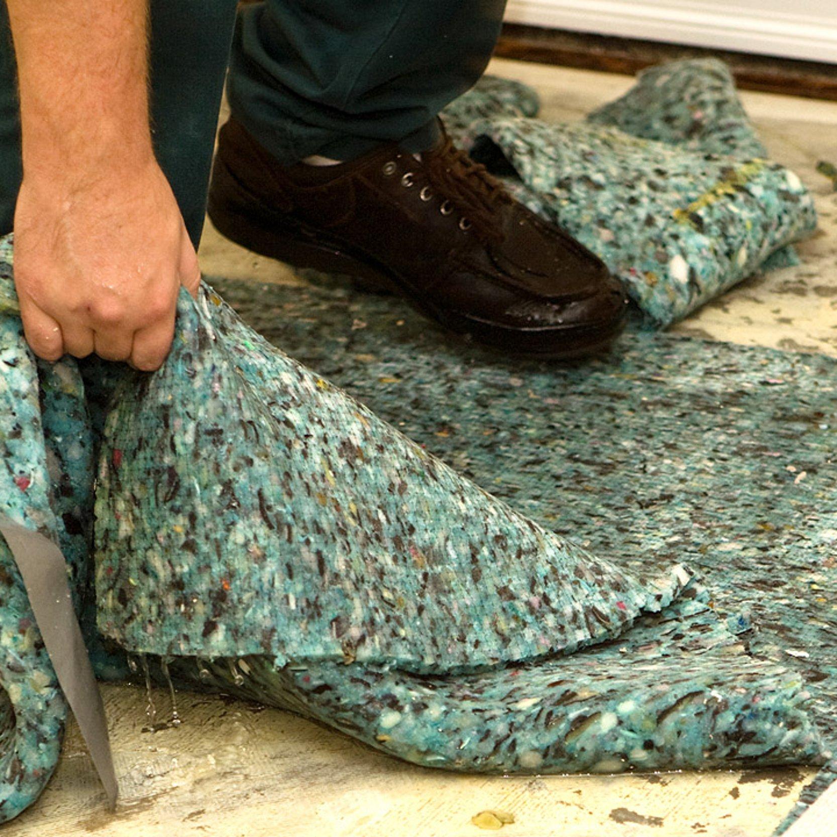 Hochwasserschaden Eine Hand zieht einen nassen Teppichboden vom schmutzigen Untergrund