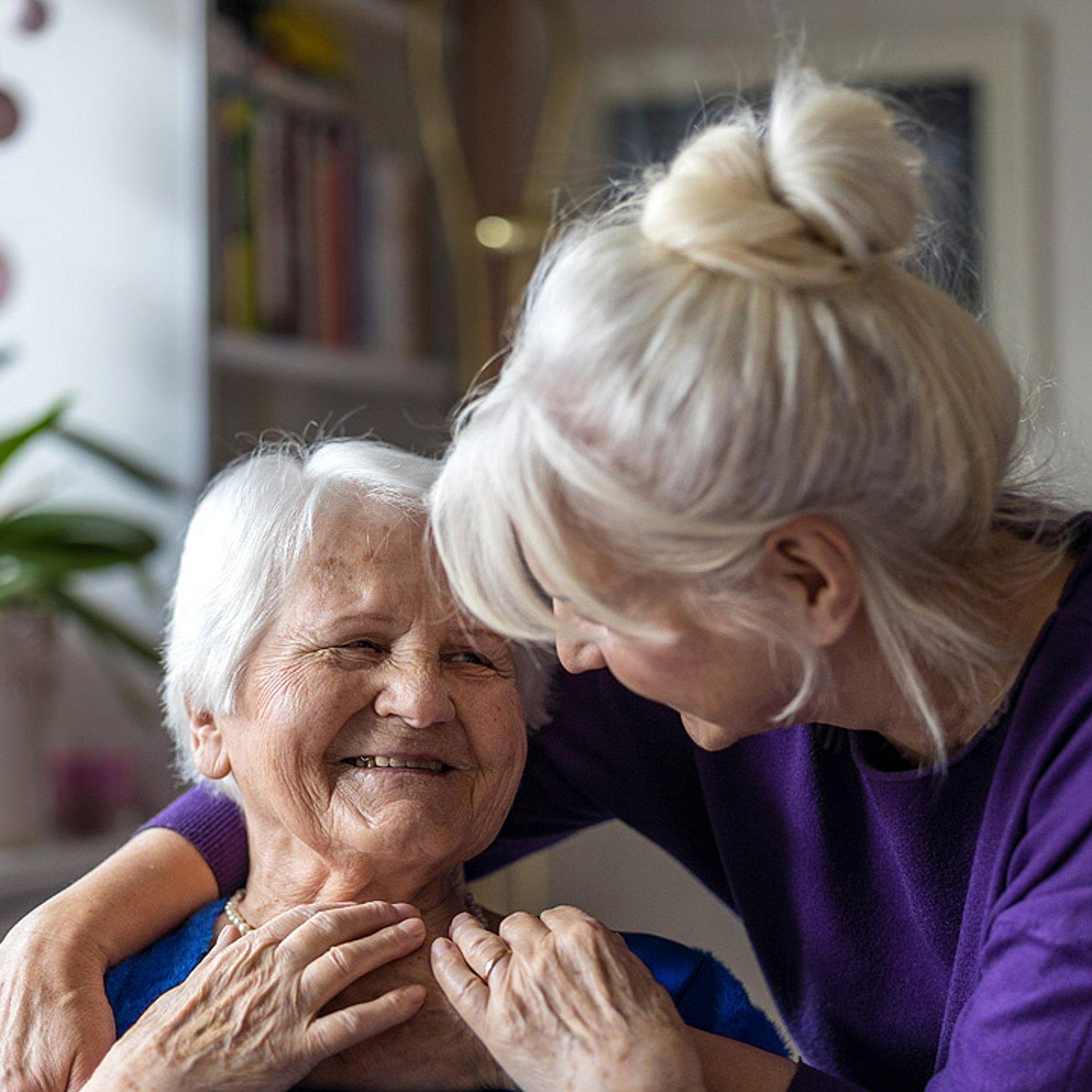 Betreuung alter Eltern Eine Frau legt den Arm um ihre alte Mutter