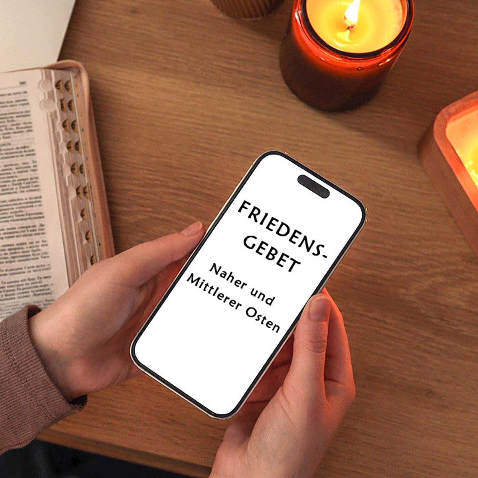 Friedengebet Kerzen, Laptop und Smartphone, auf dem "Friedensgebet - Naher und Mittlerer Osten " steht