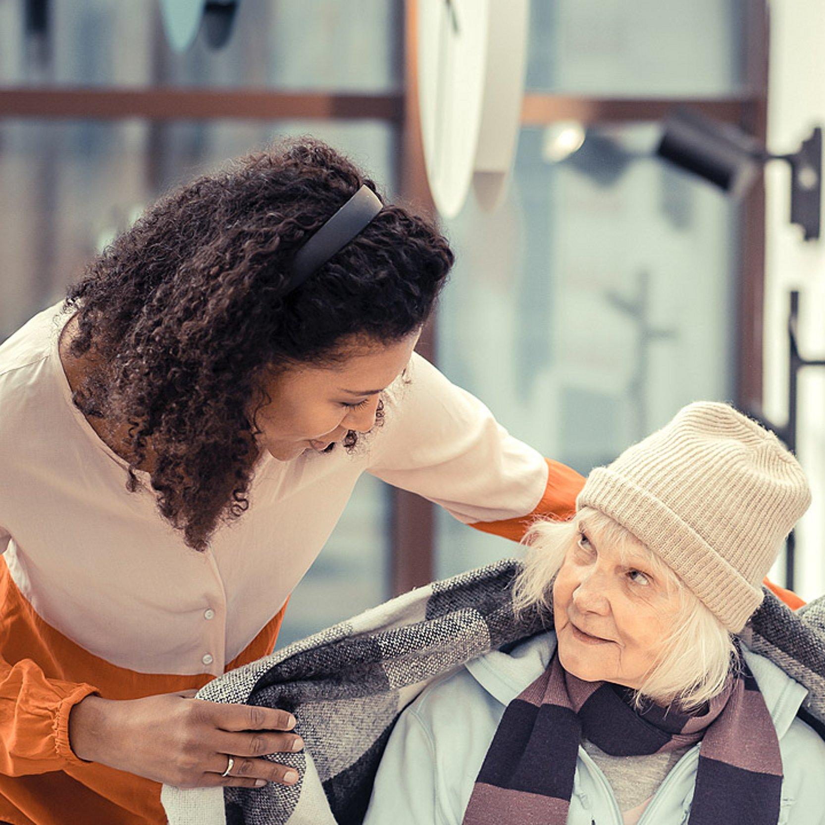 Diakonie hilft Obdachlosen Eine Frau legt eine wärmende Decke um eine alte, obdachlose Frau