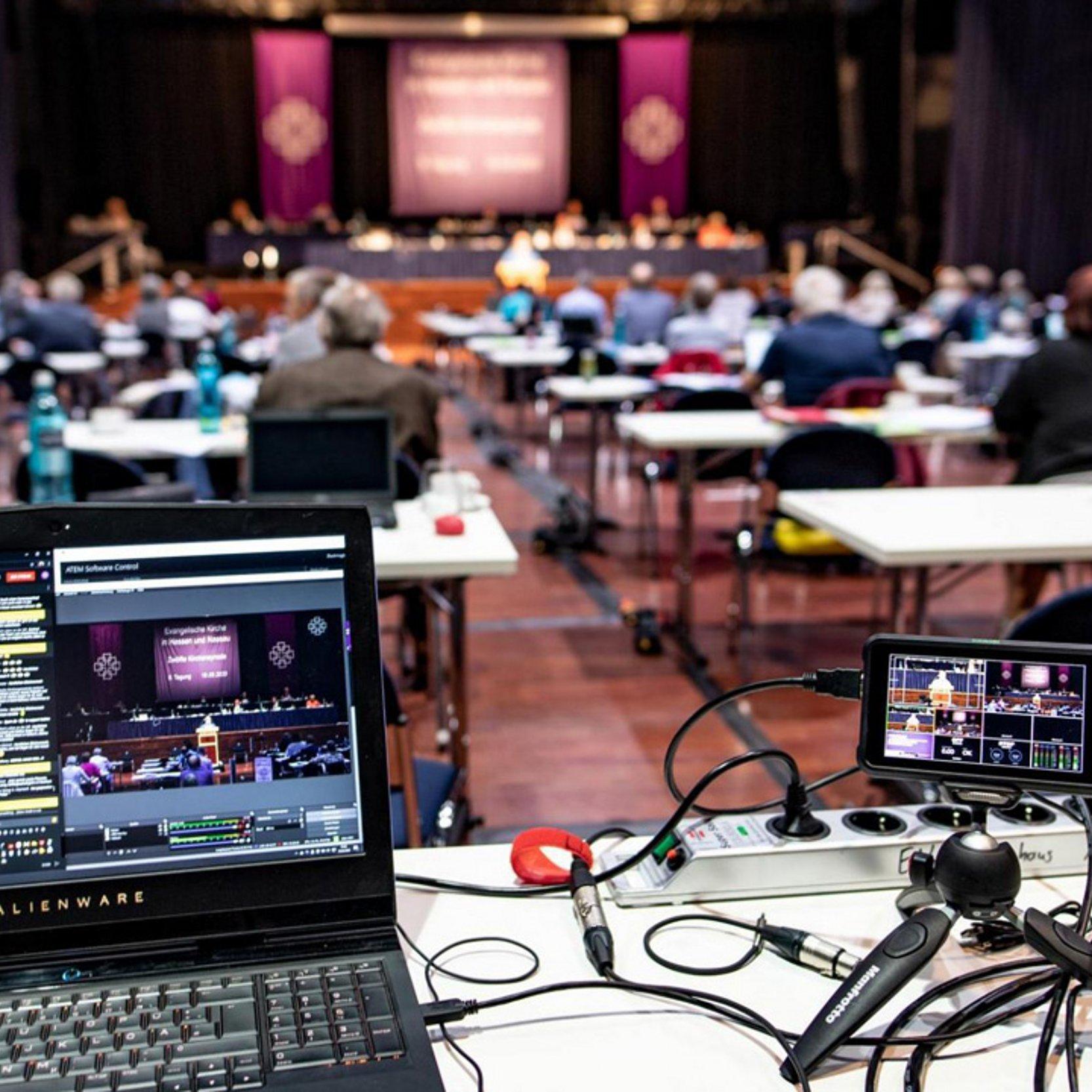 Übertragungstechnik auf der Kirchensynode großer Raum der Kirchensyode, Ein aufgeklappt Laptop im Vordergrund, daneben Aufzeichnungstechnik