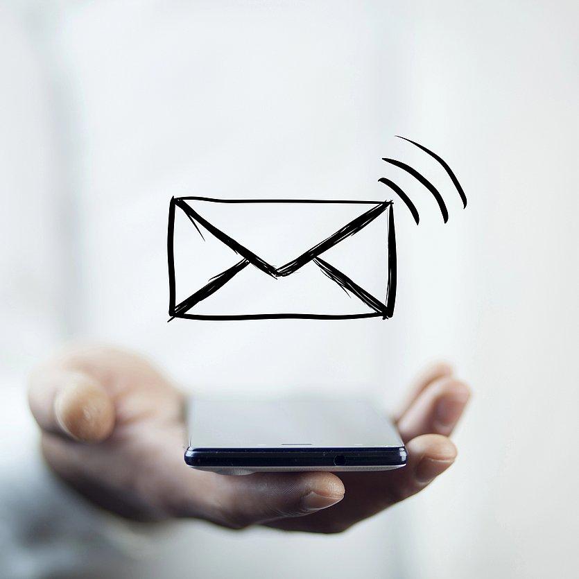 head_newsletter Hand mit Smartphone, darüber ein gezeichneter Briefumschlag als Symbol für den elektronischen Newsletter