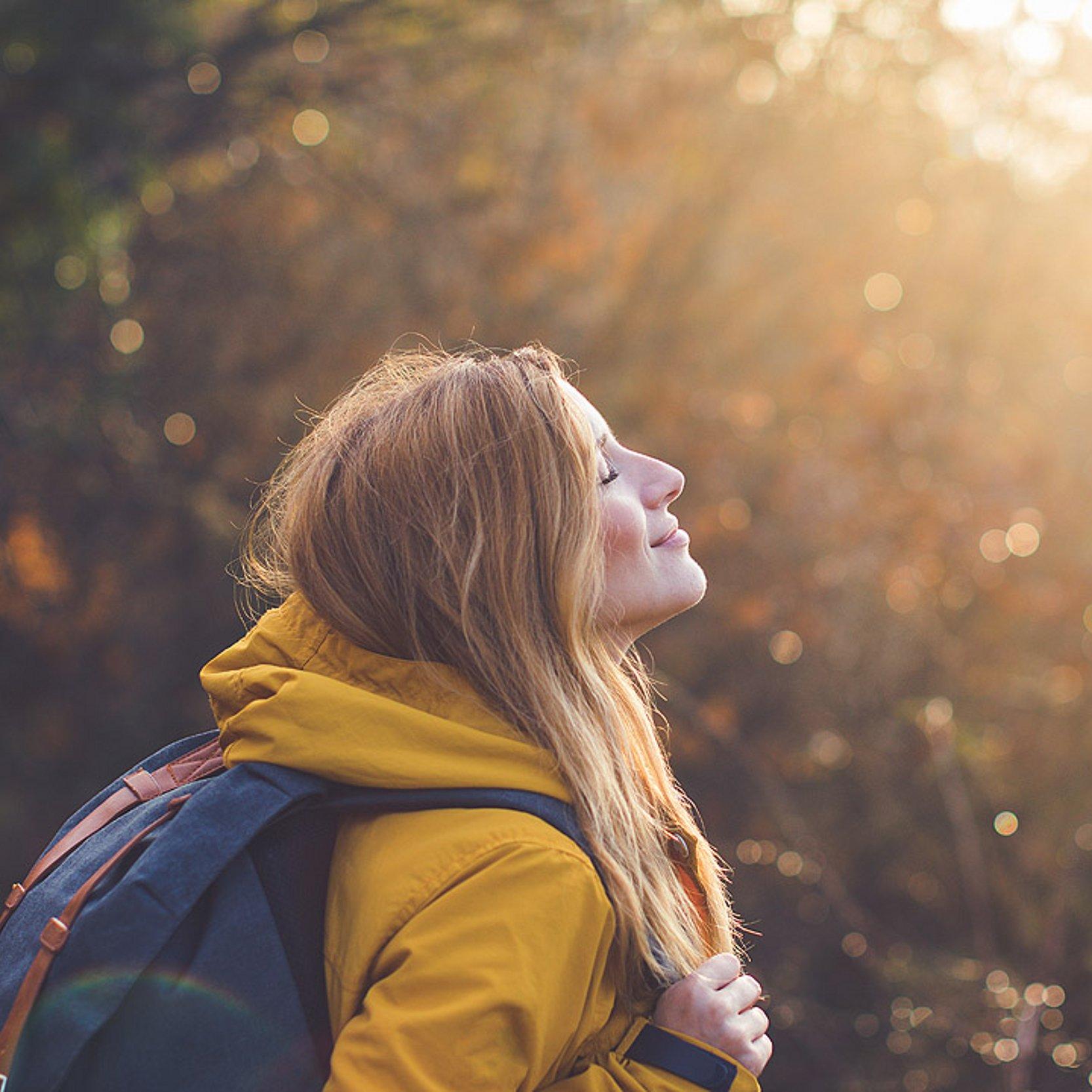 Pilgern im Herbst Eine Frau blickt in einer herbstlichen Umgebung Richtung Sonne