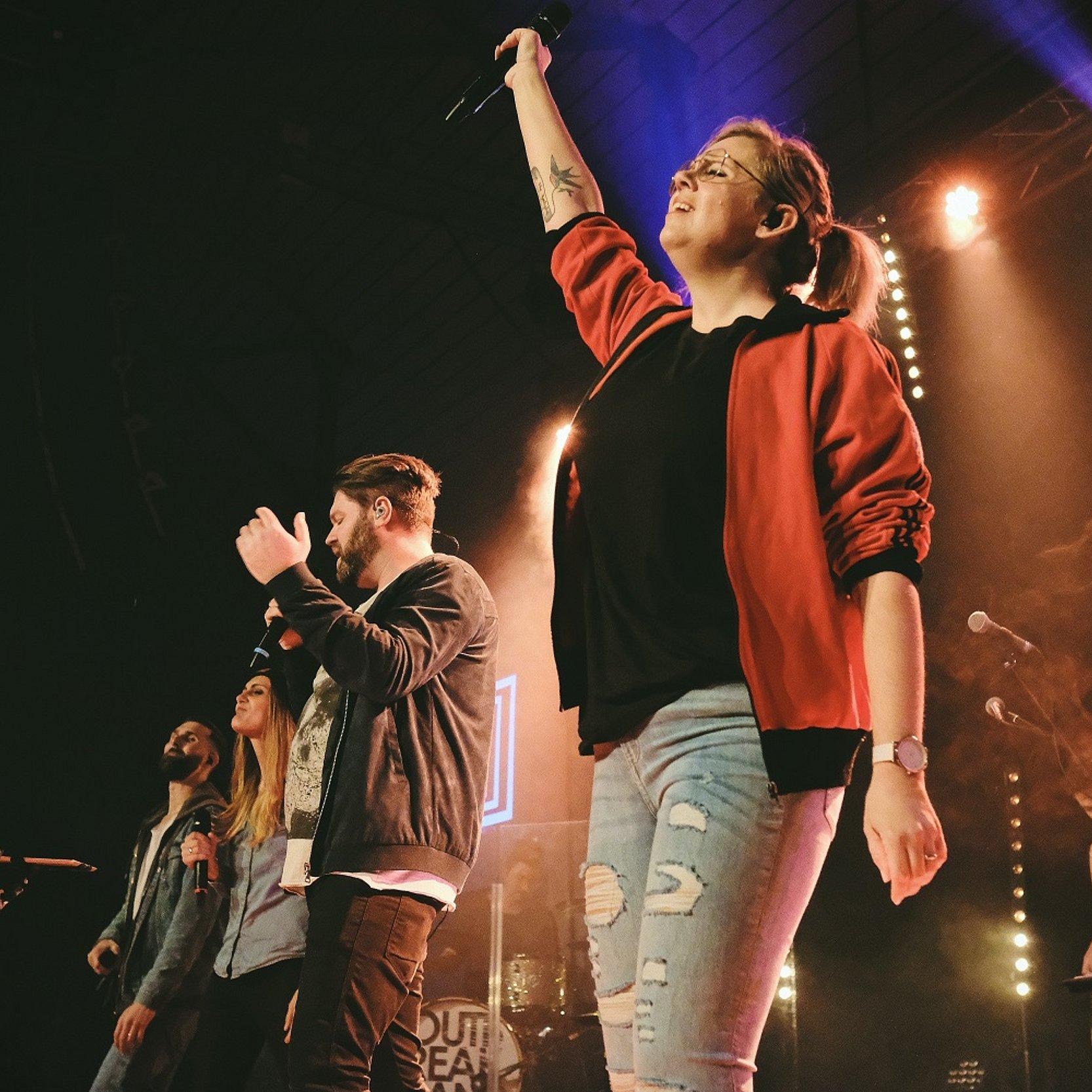 Kirche rockt. Menschen machen Rockmusik auf einer Bühne.