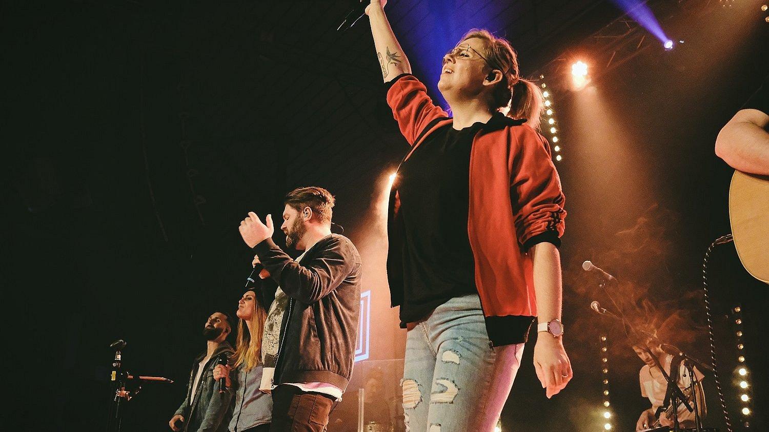 Kirche rockt. Menschen machen Rockmusik auf einer Bühne.