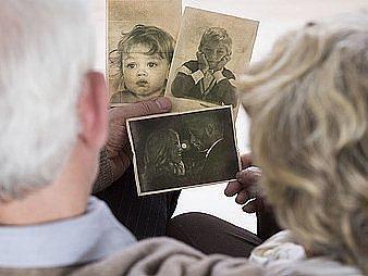 Zwei Senioren schauen auf verschiedene alte Kinderfotos