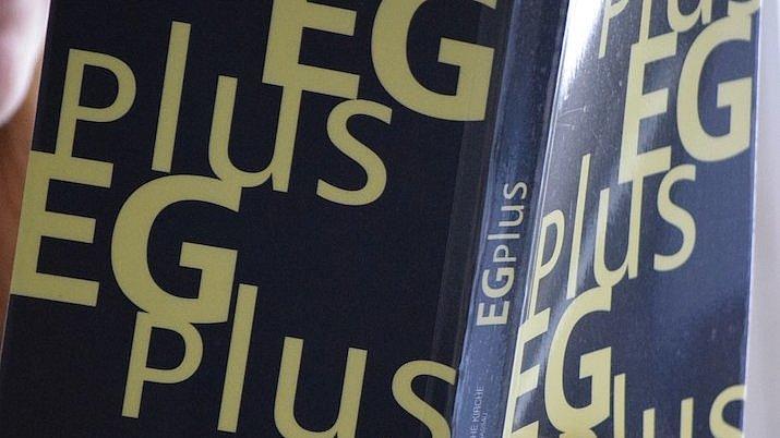 EGplus Ein Mensch hält ein aufgeschlagenes Gesangbuch in Händen.