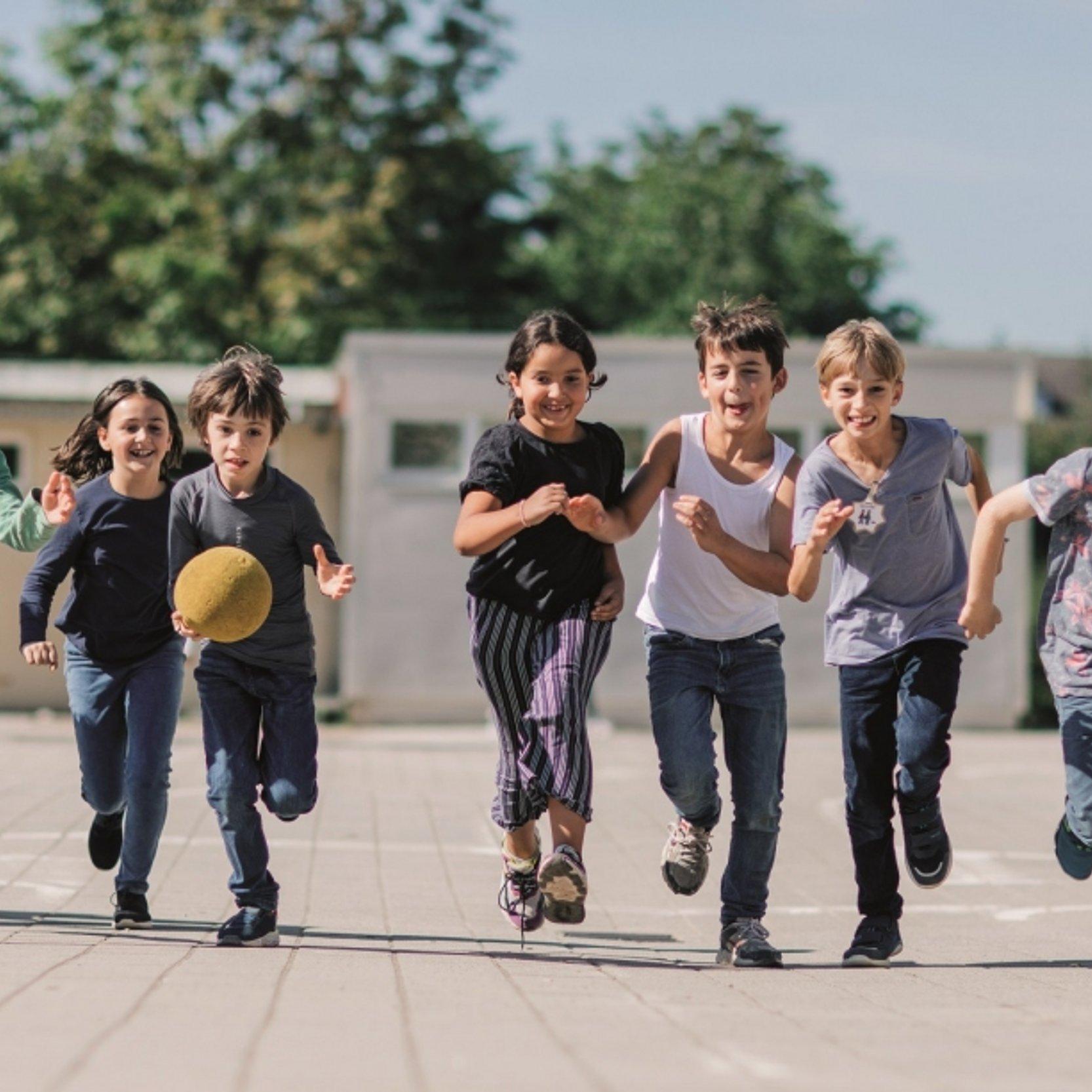 40 Jahre Margarte-Steiff-Schule Eine Gruppe Kinder rennt gemeinsam über den Schulhof aus die Kamera zu.