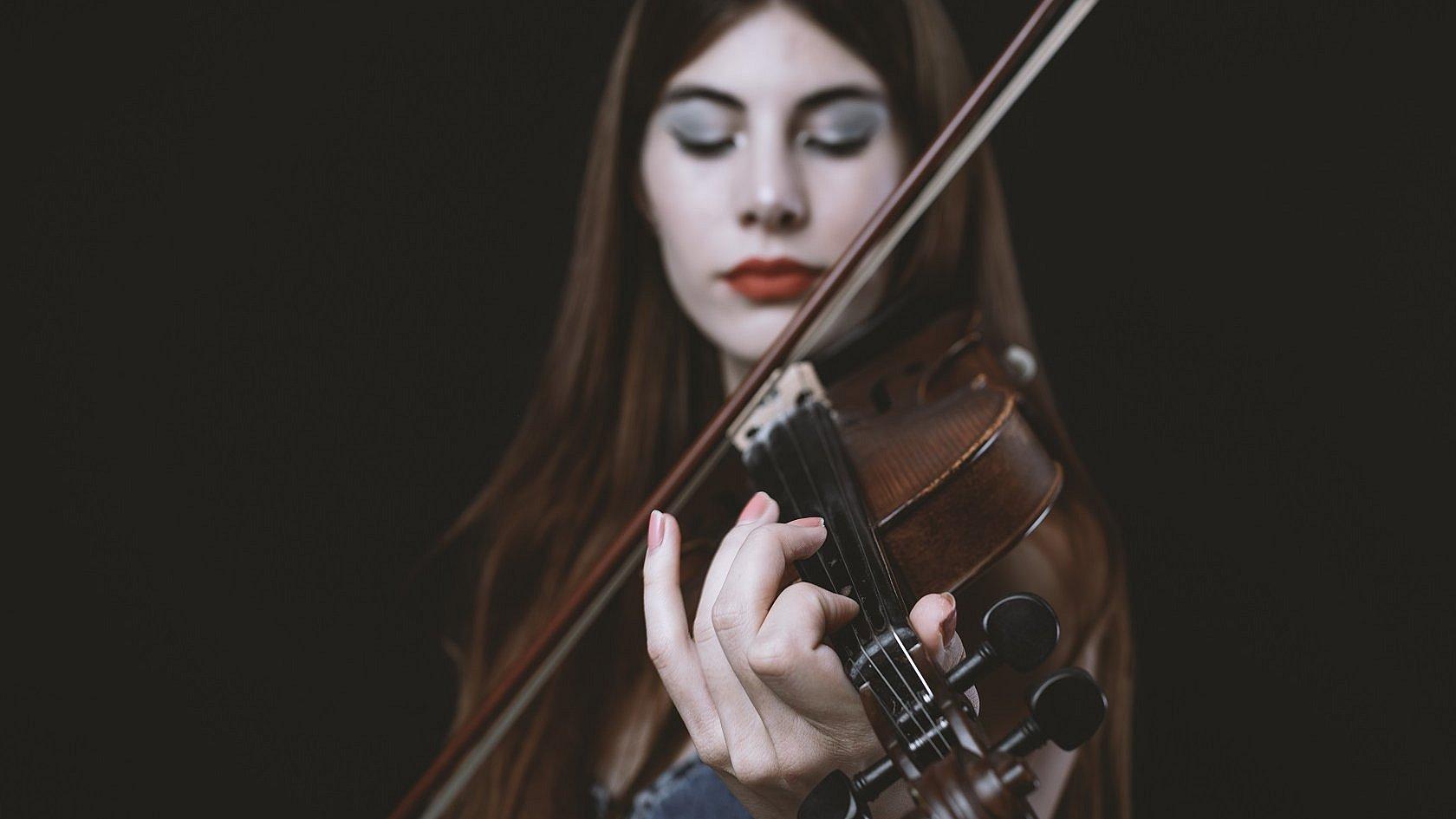 Frau spielt vertieft und nachdenklich auf der Geige.