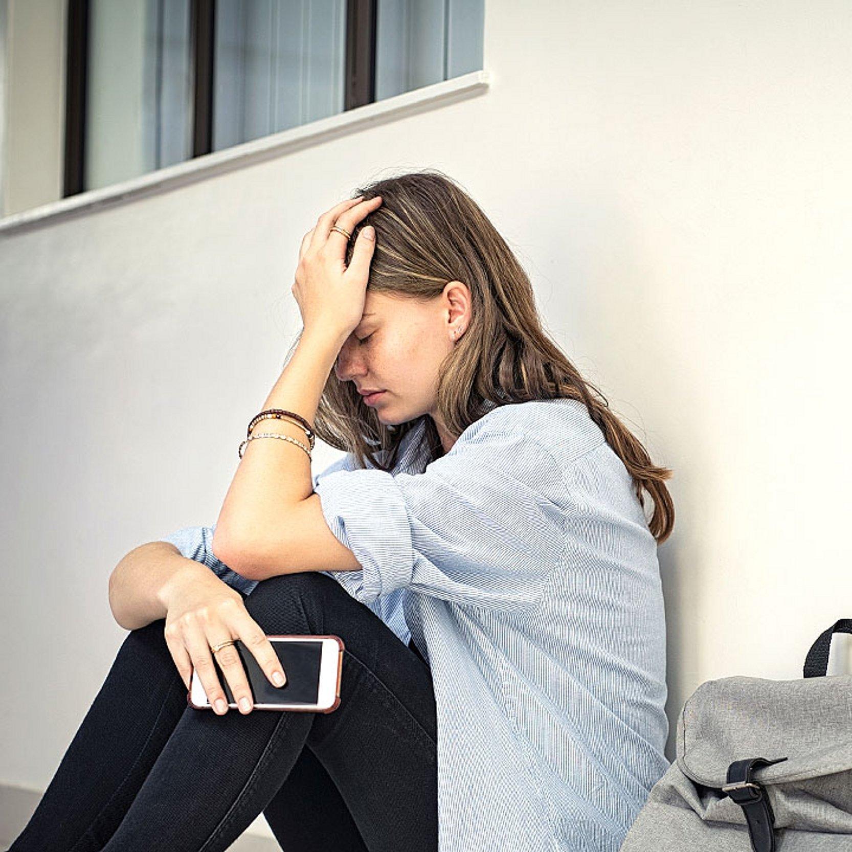 Verzweiflung Ein Mädchen sitzt am Boden und verbirgt den Kopf in den Händen