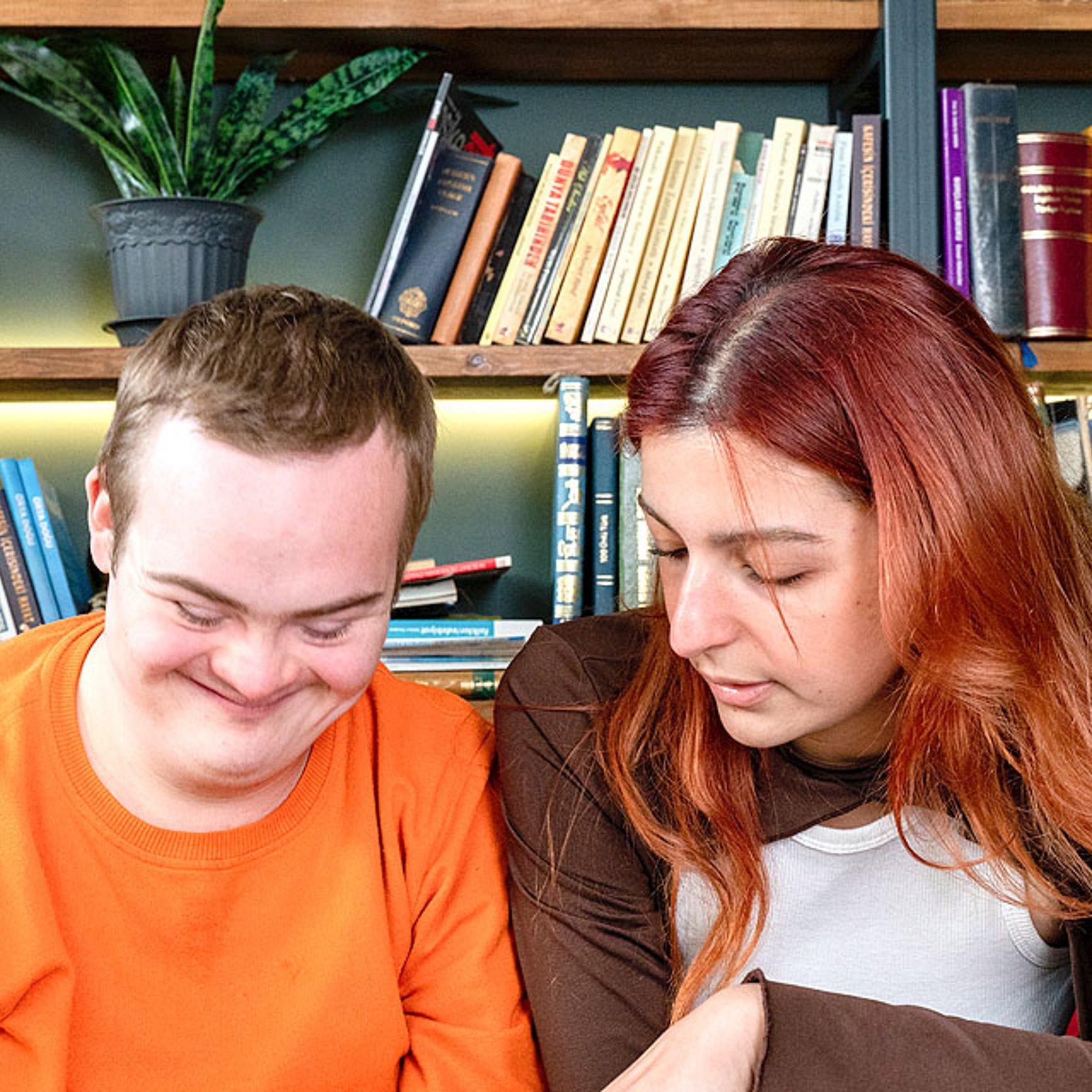 Inklusion Eine Frau zeigt einem behinderten, jungen Mann den Umgang mit einem Laptop