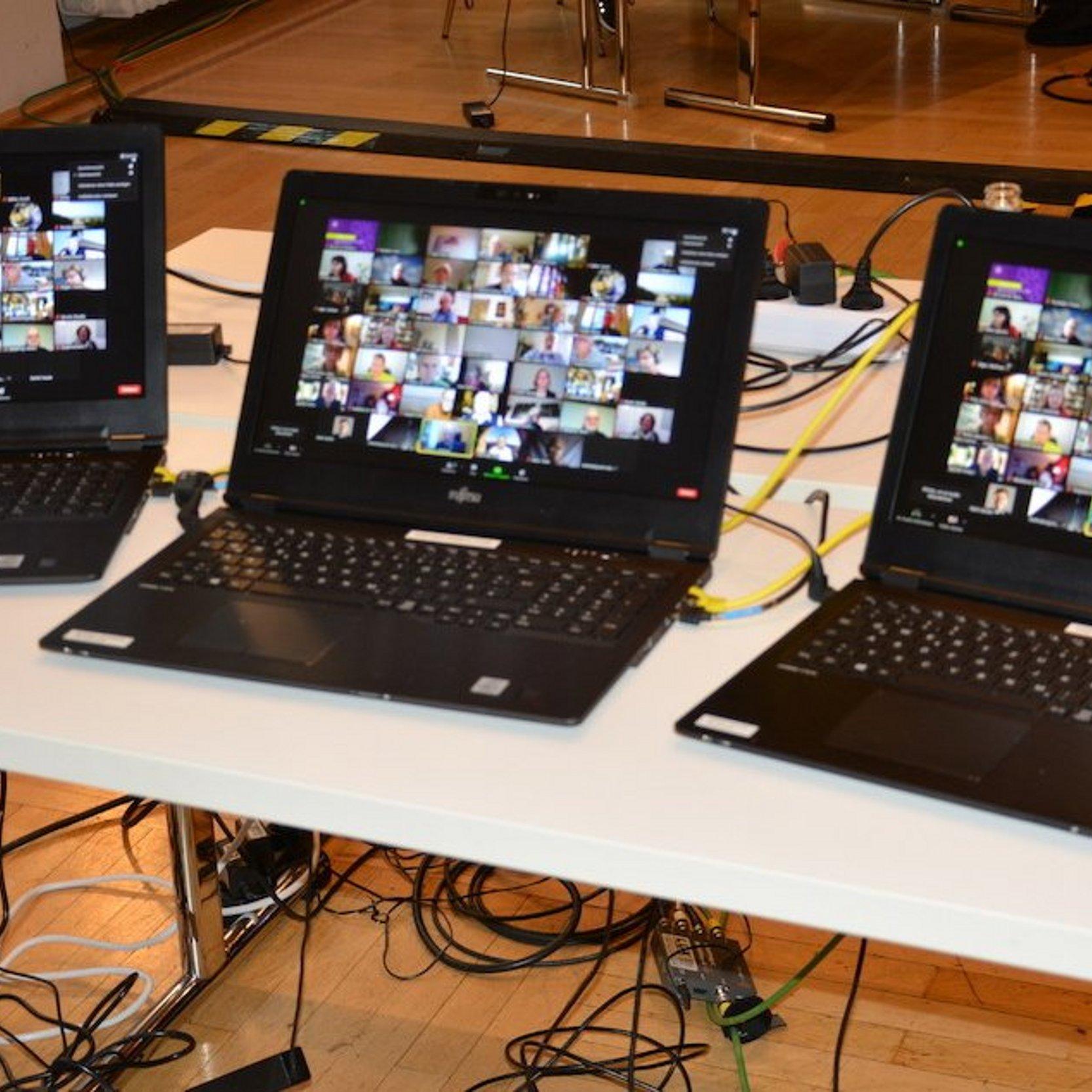 drei angeschaltete und aufgeklappte Laptops