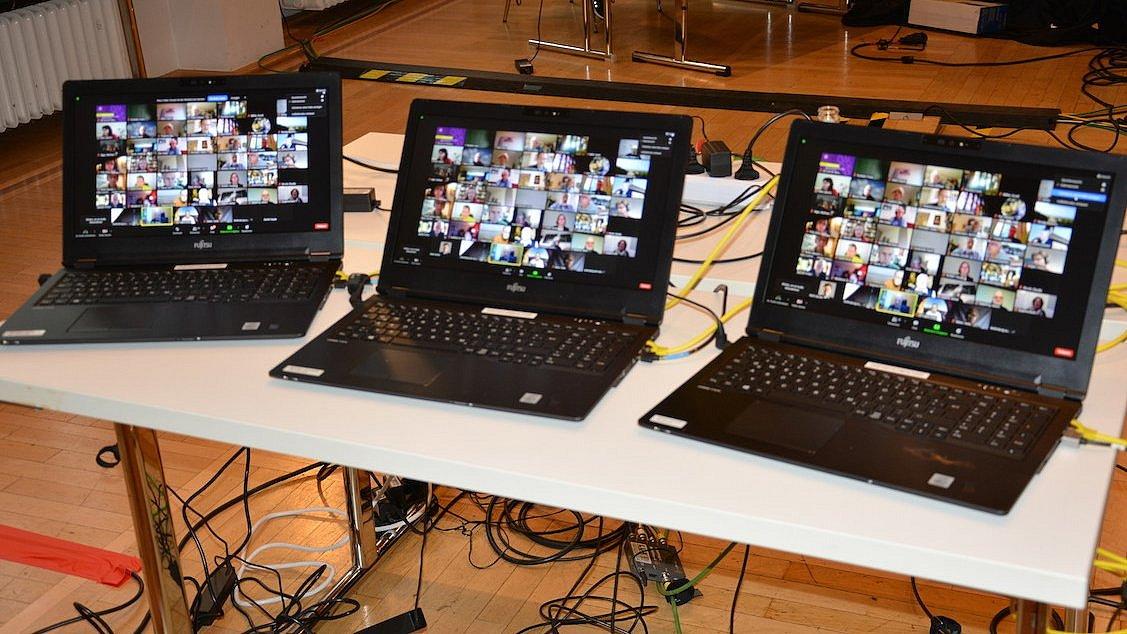 drei angeschaltete und aufgeklappte Laptops