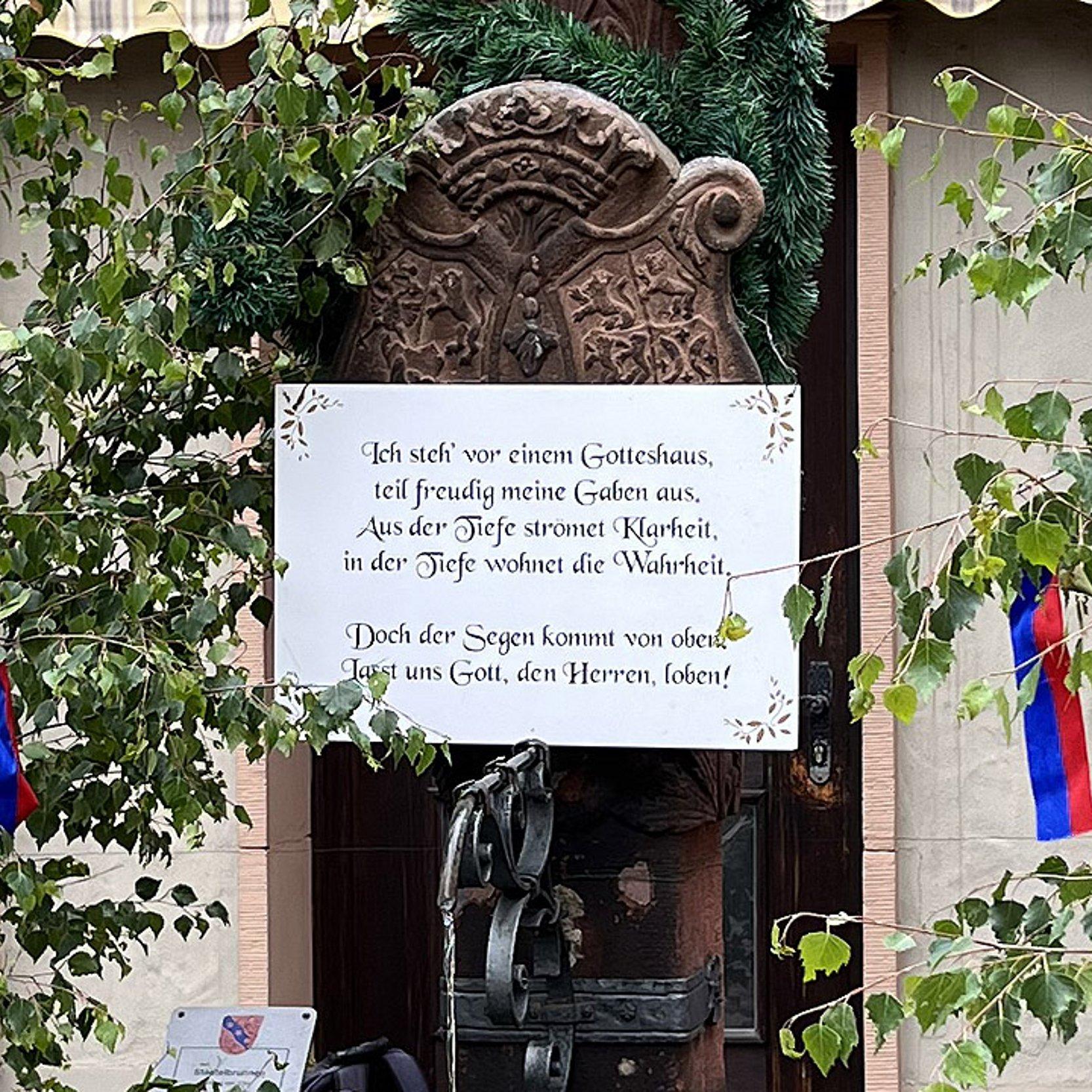 Pfingstbrunnen Birkengrün mit Bändern um einen Brunnen mit dem Schild: Ich steh vor einem Gotteshaus, teil freudig meine Gaben aus. Aus der Tiefe strömet Klarheit, in der Tiefe wohnet die Wahrheit. Doch der Segen kommt von oben. Lasst uns Gott, den Herrn loben!
