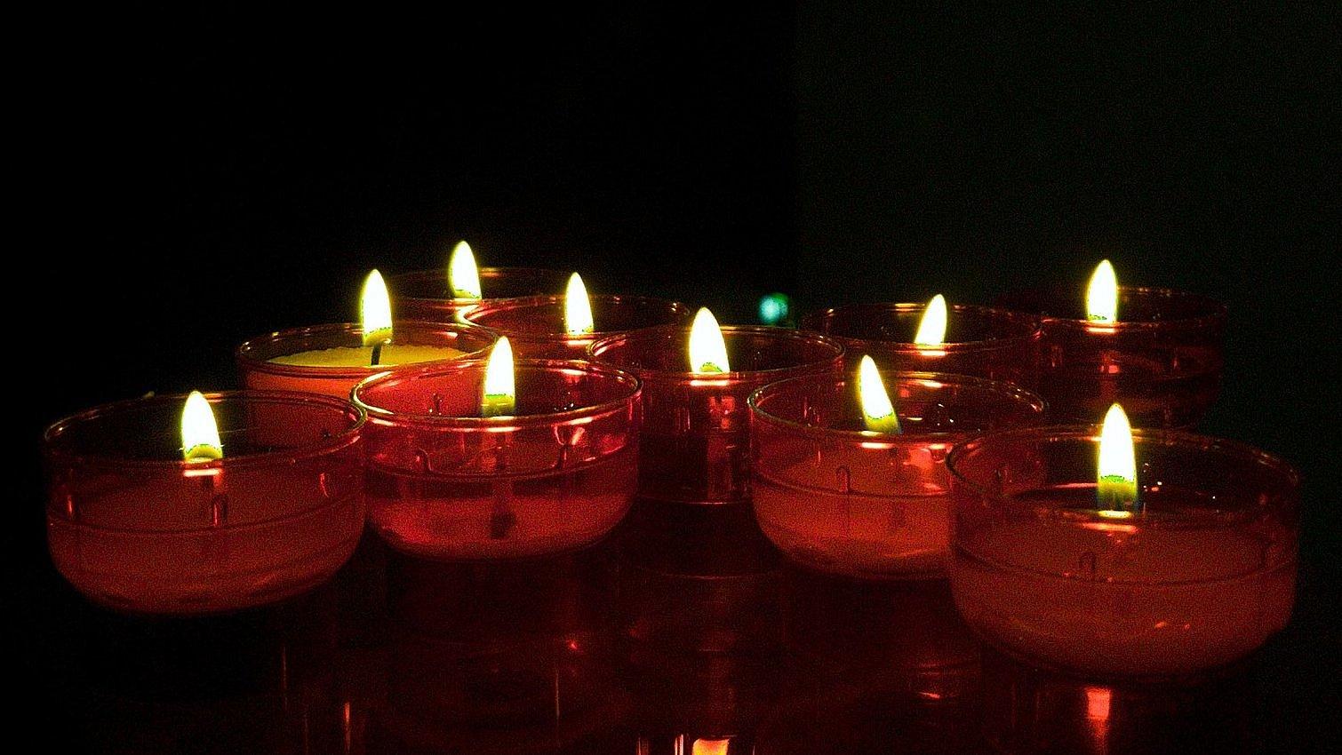 Kerzen leuchten in dunkler Kirche