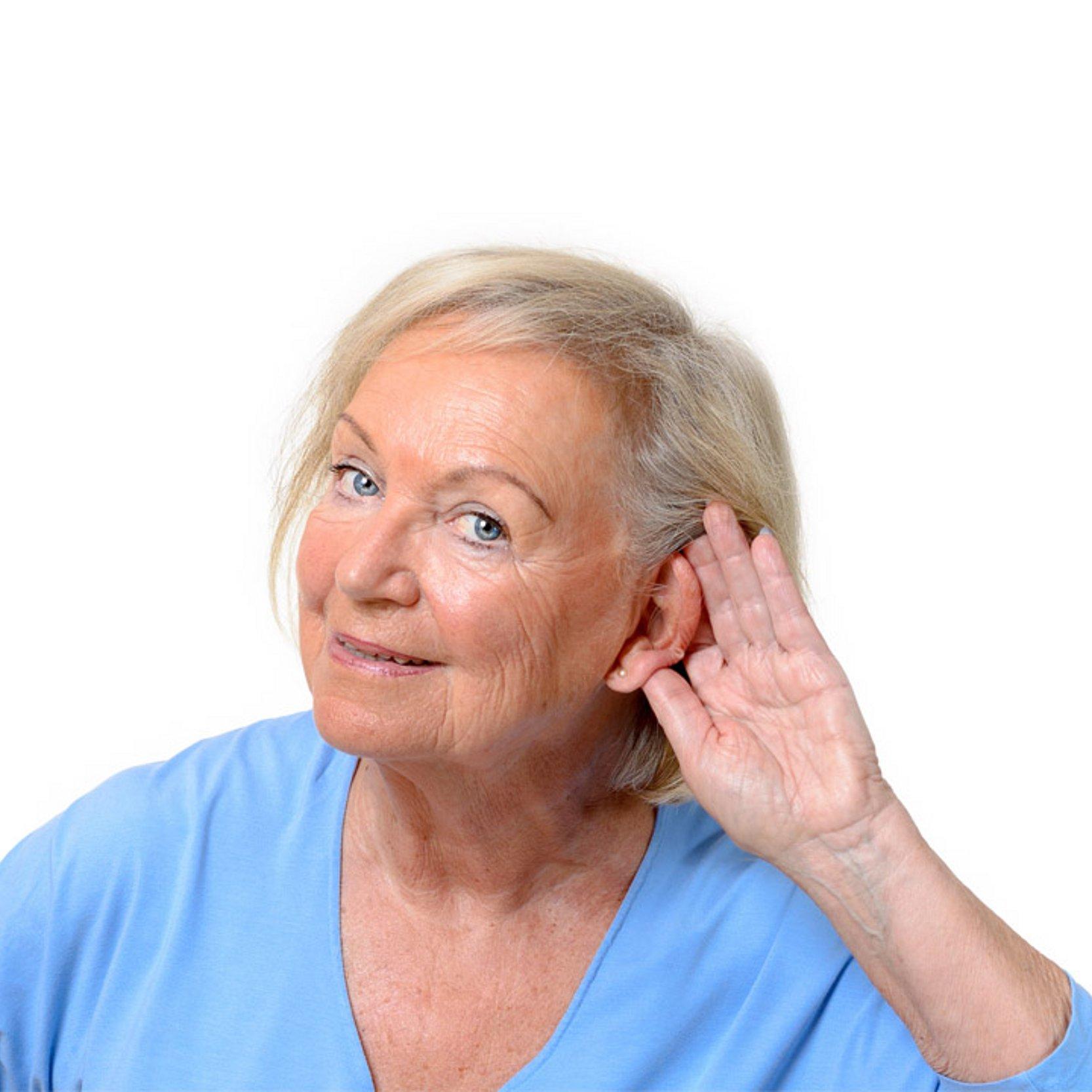 Schwerhörigkeit Eine ältere Dame, die die Hand hinter ihre Ohrmuschel hält