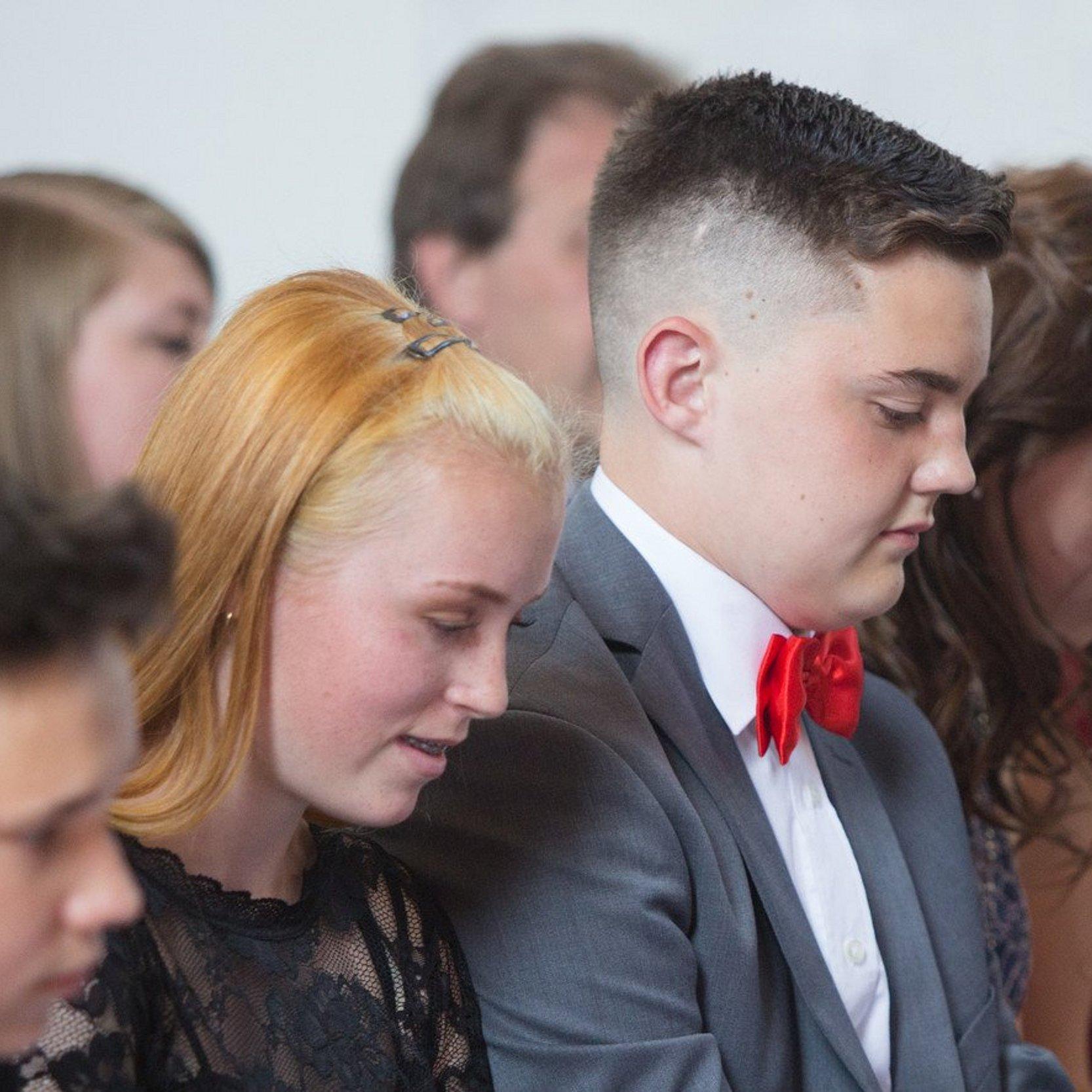 Konfirmation Konfirmanden 3 Jugendliche sitzen in einer Kirchenbank und singen