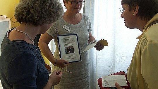 Eine Dame zeigt eine Urkunde.