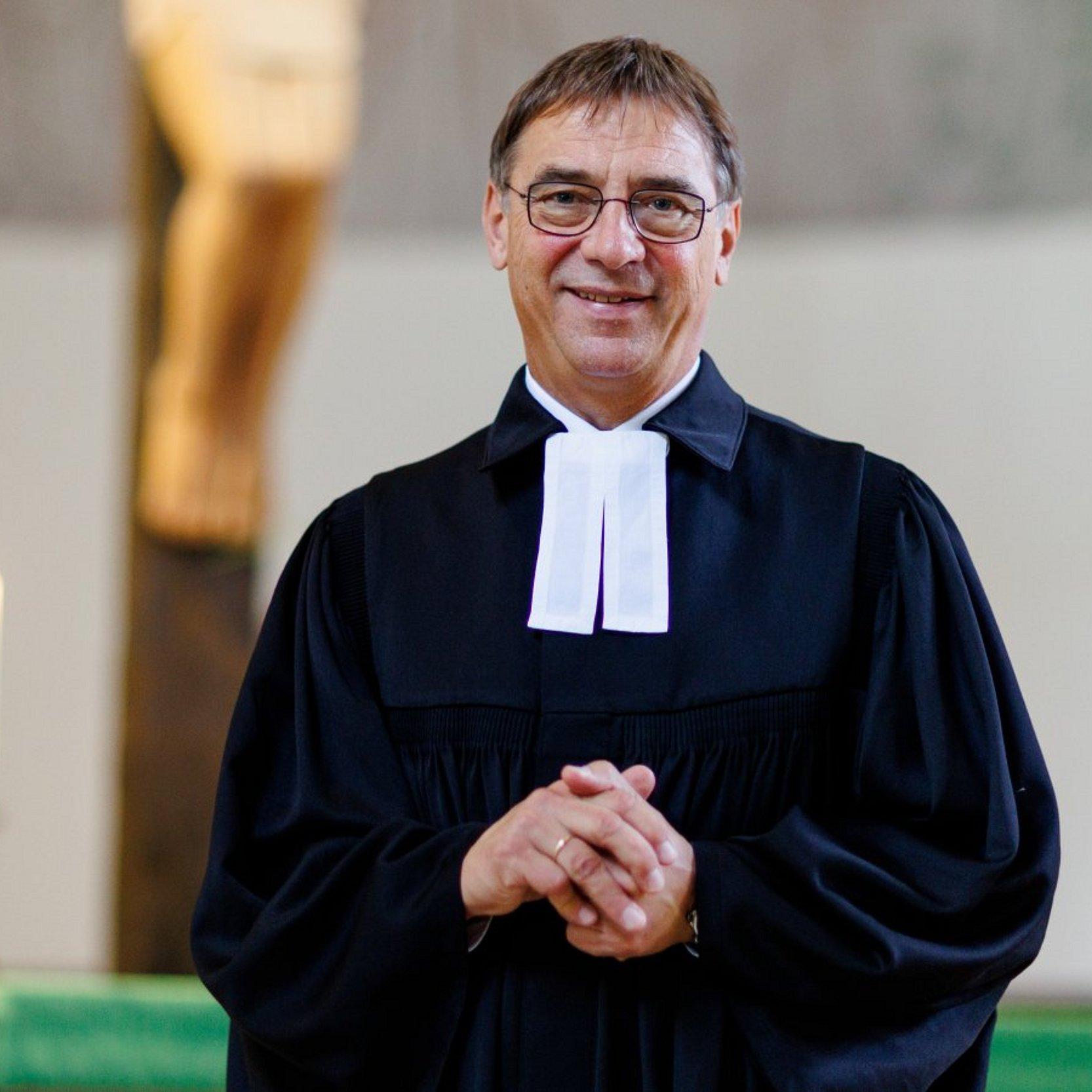 Kirchenpräsident Dr. Volker Jung Portrait, steht vor dem Altar mit einer brennenden Kerze